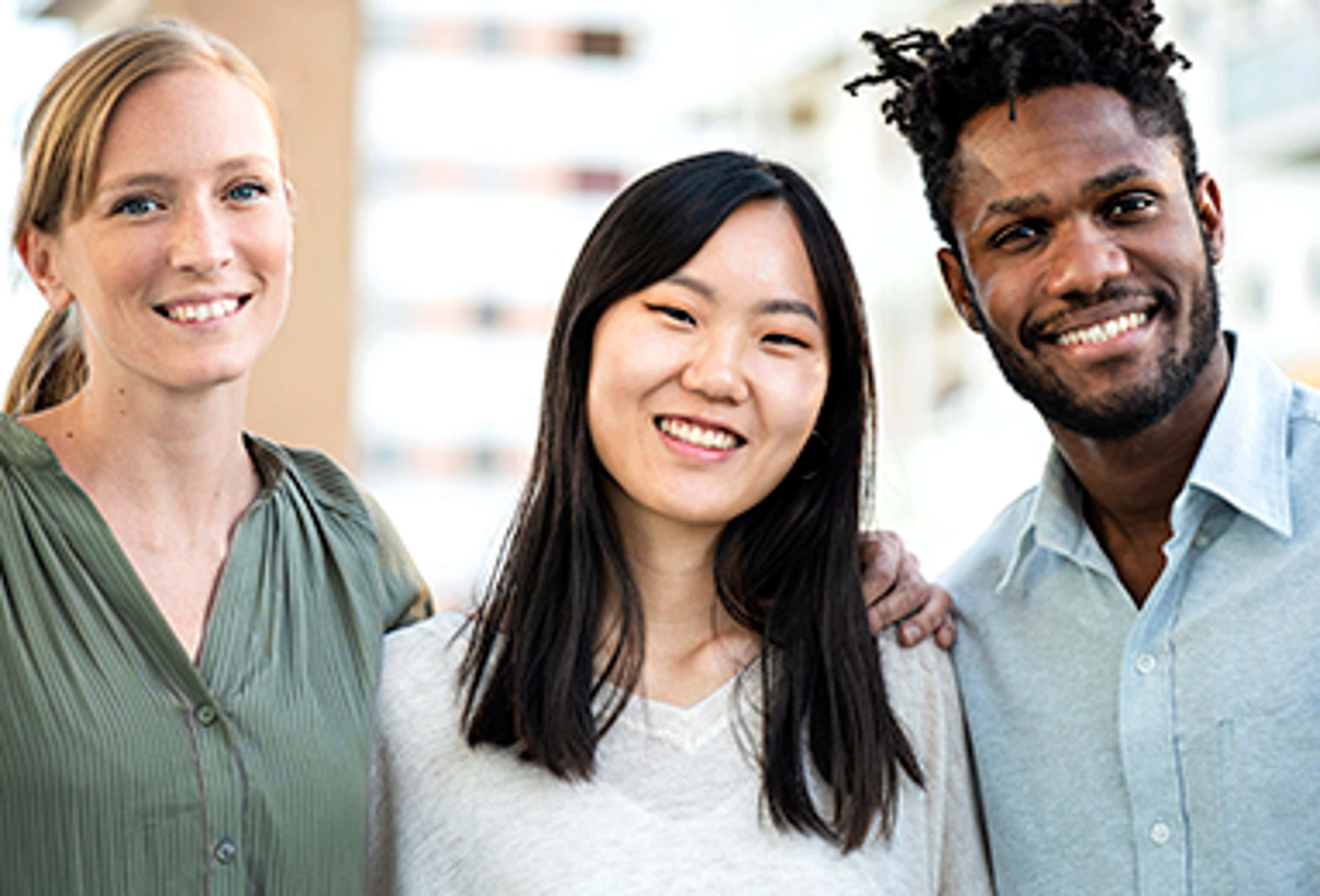 Three students standing together smiling at the camera