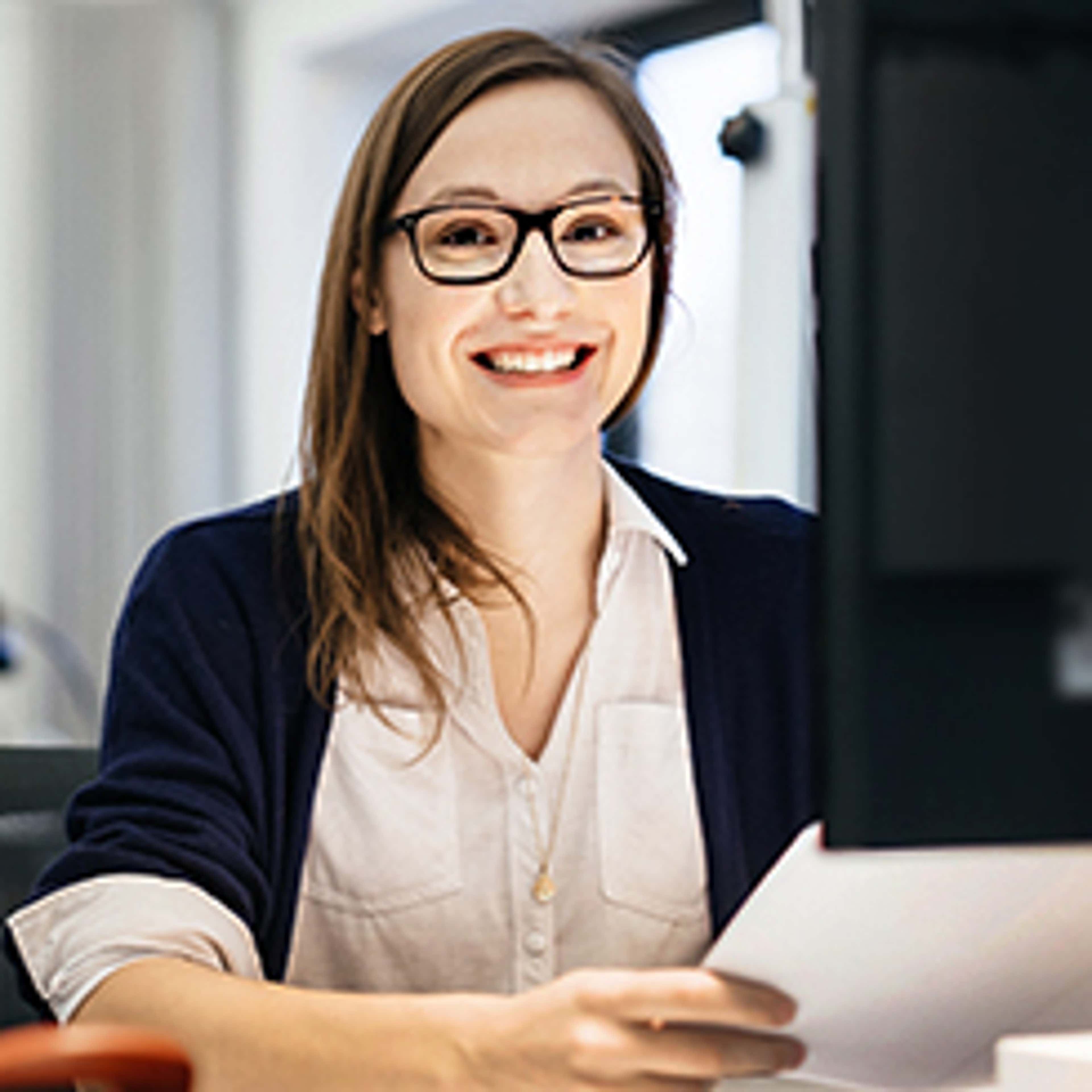 Person with glasses smiling looking at camera