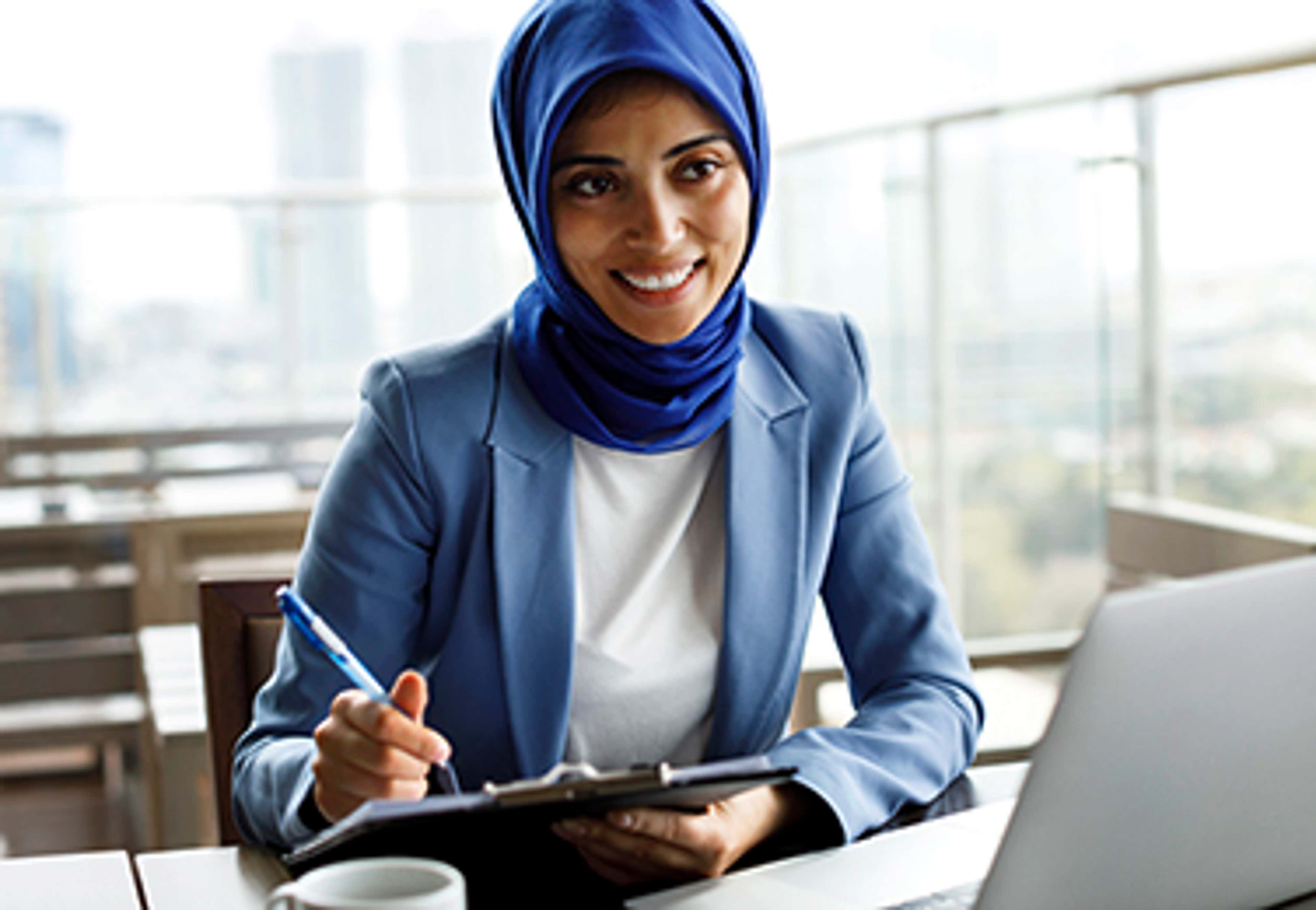 Person at table with laptop and notepad
