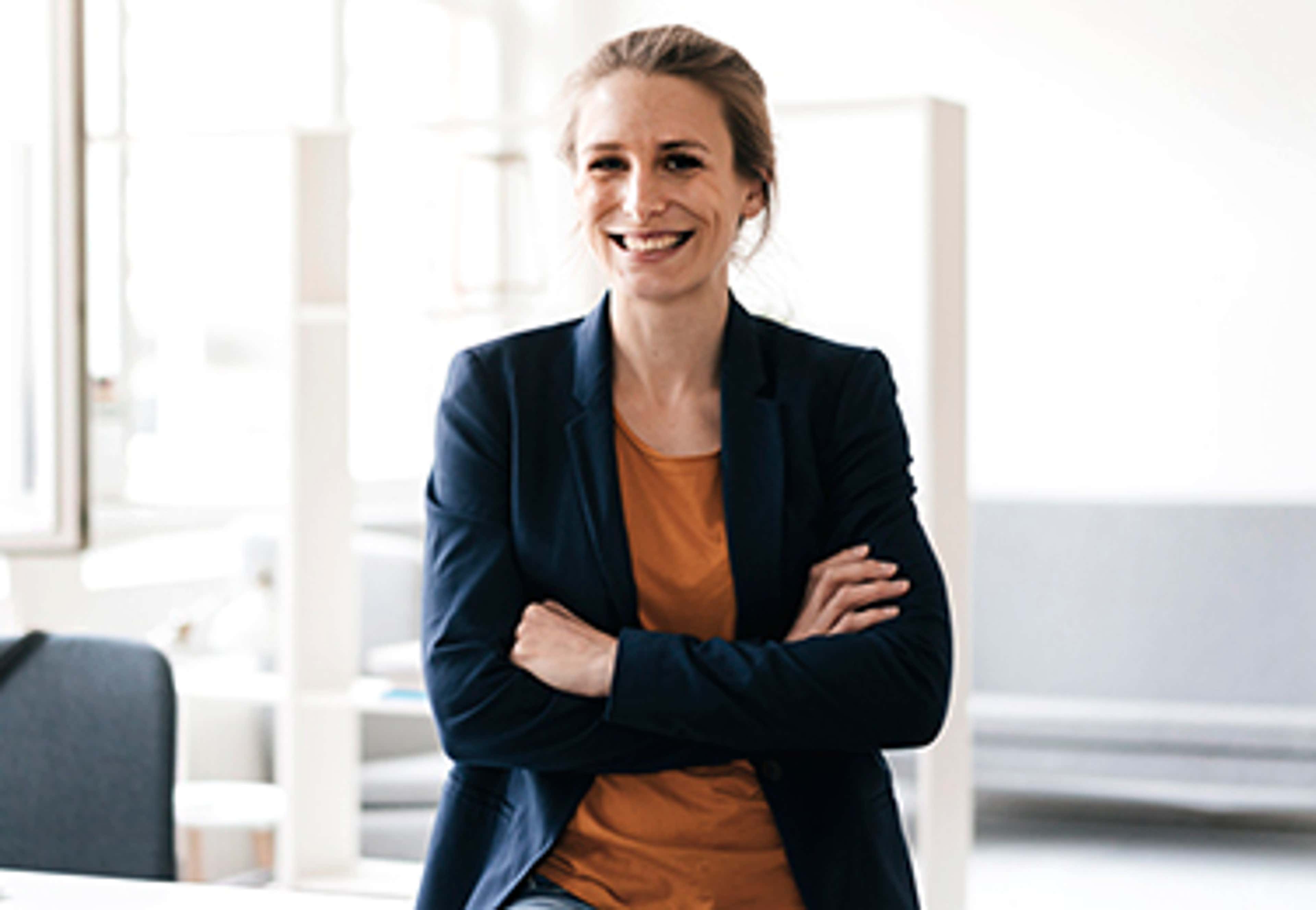 Person standing with arms crossed smiling at camera
