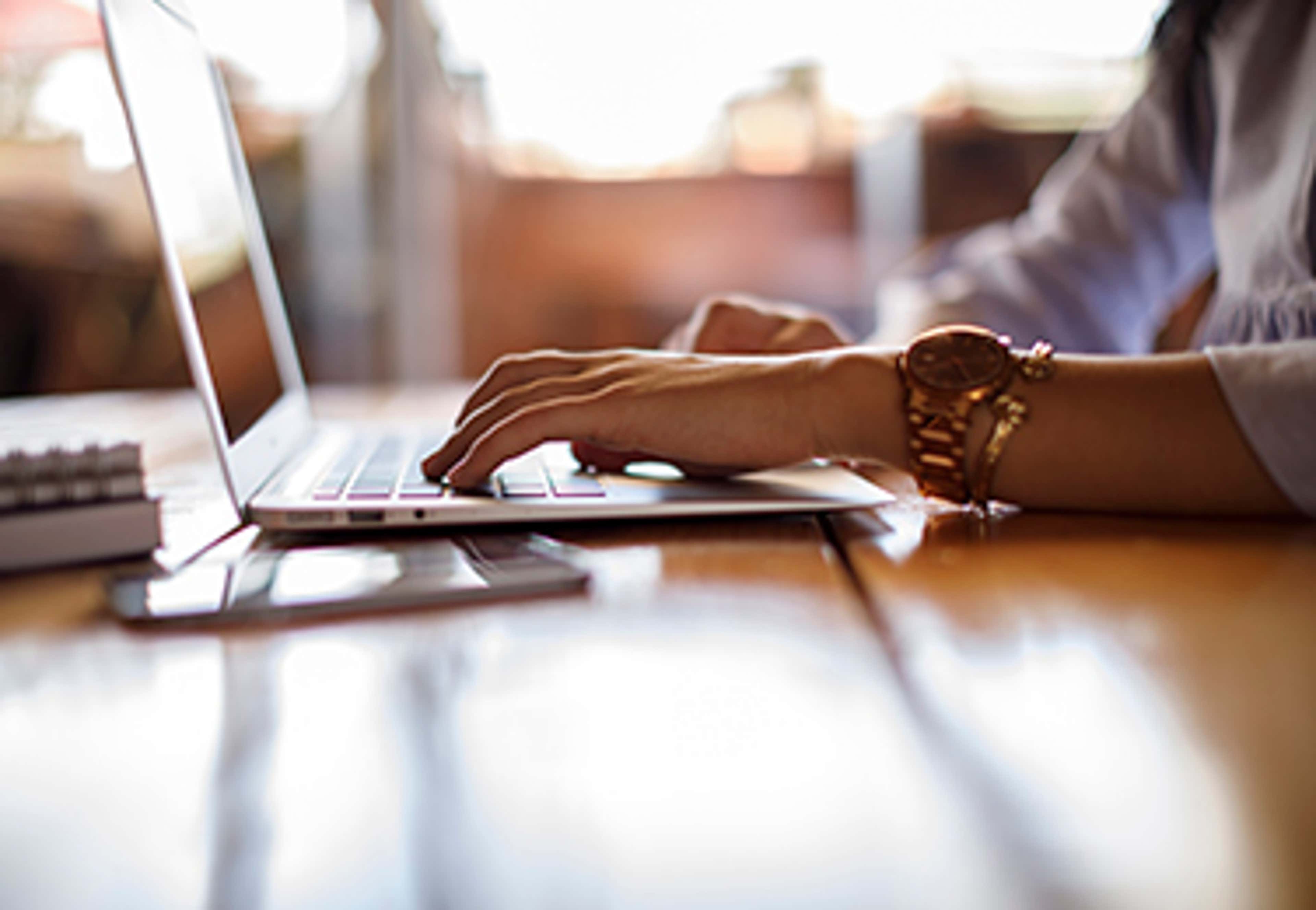 Person typing on laptop on wood desk