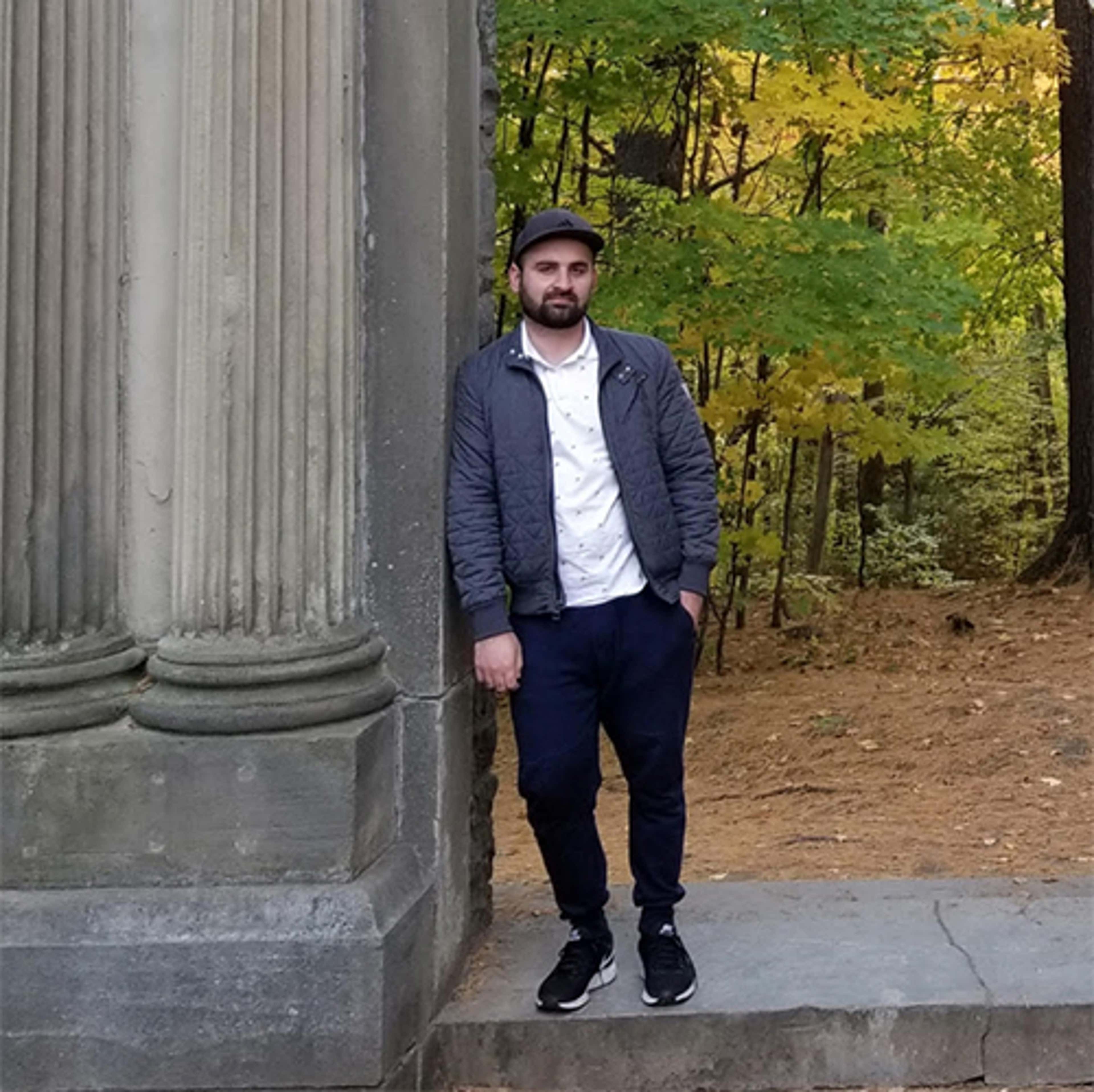 Photo of Ahtisham Fazli outside leaning against a stone column