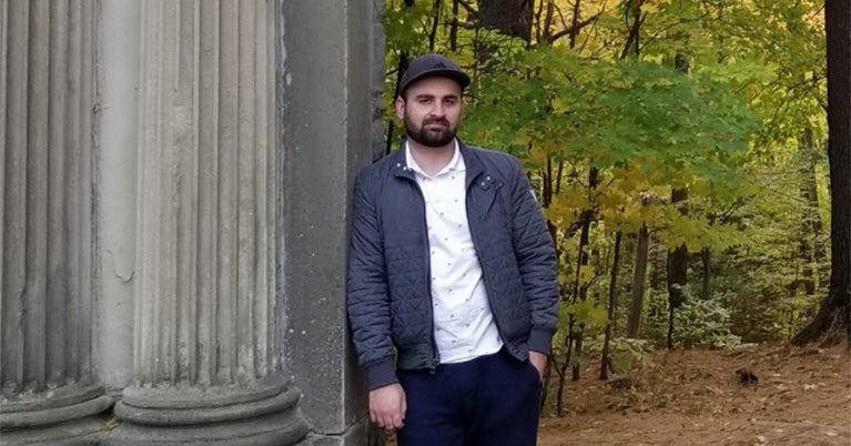 Photo of Ahtisham Fazli outside leaning against a stone column