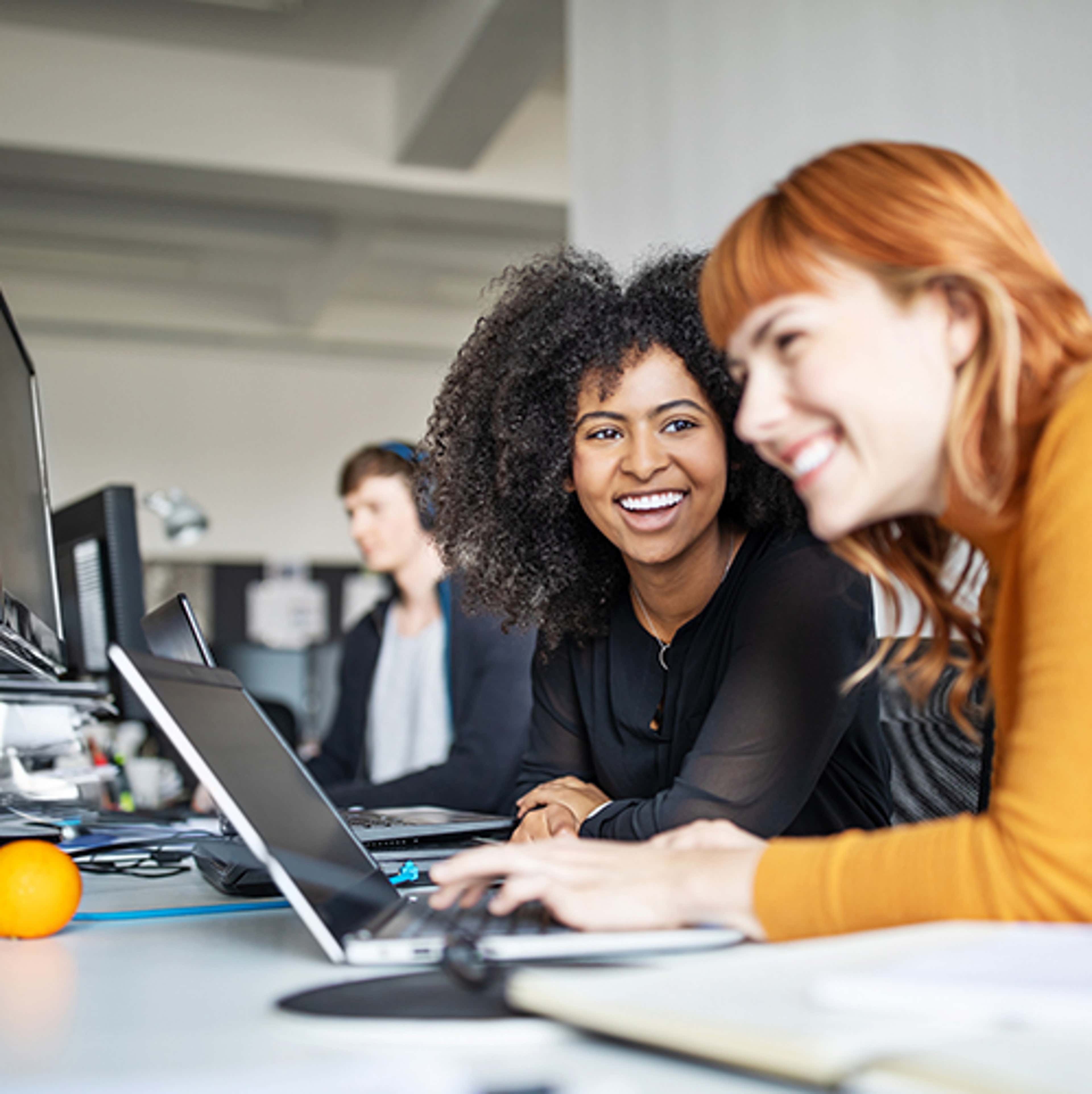 Two women at desk with laptop laughing