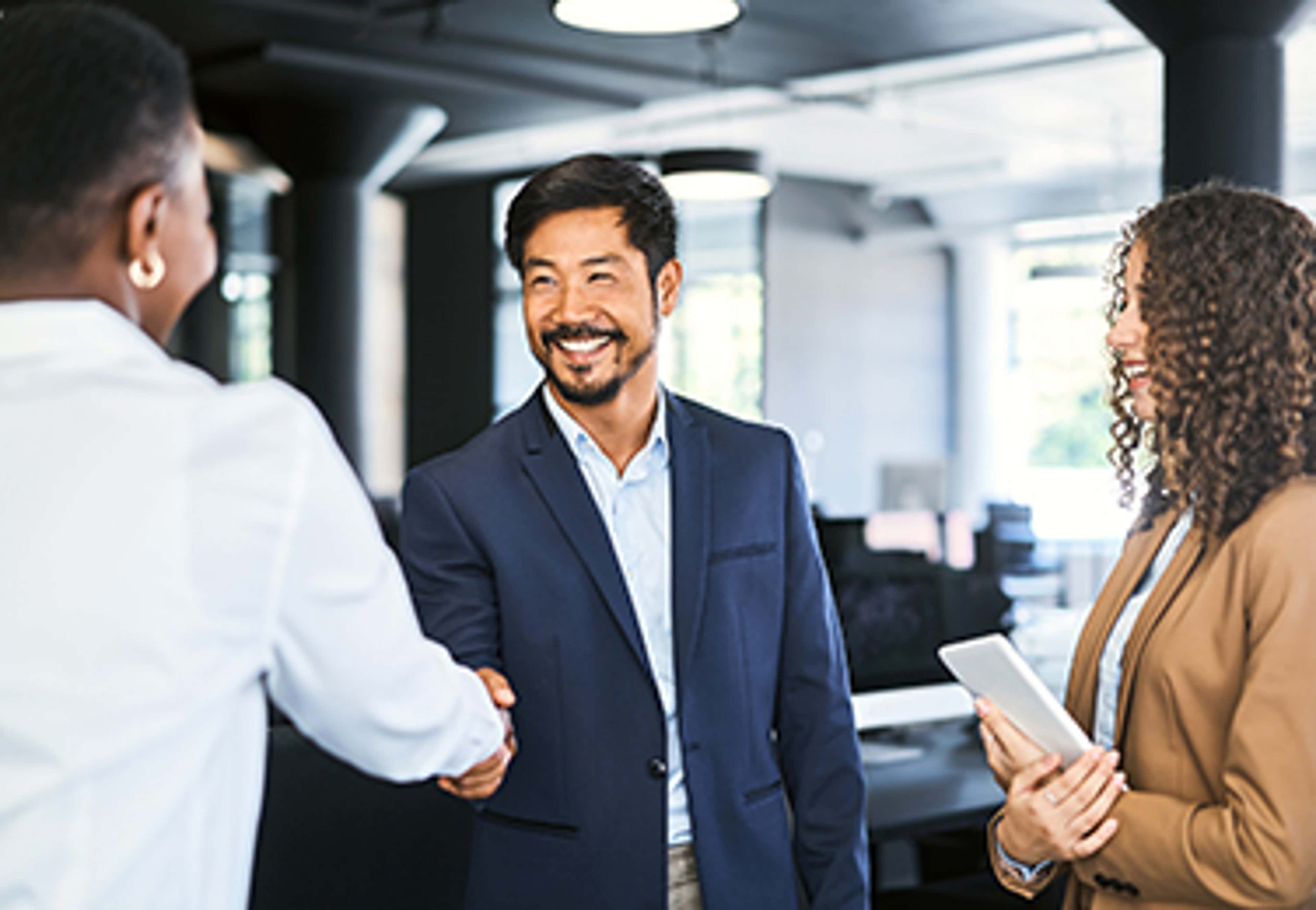Man in blue suit jacket in office shaking hands with another person