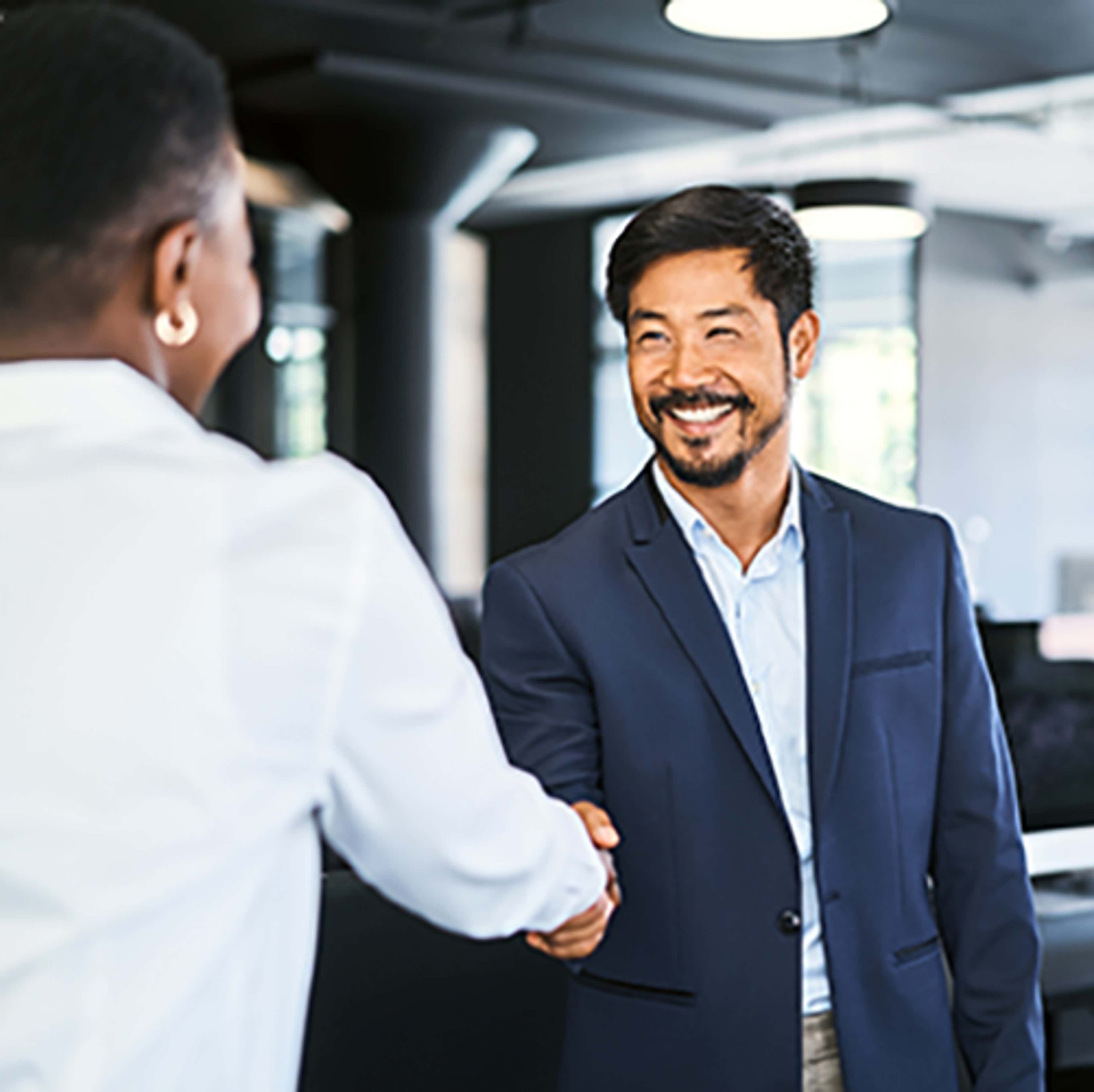 Man in blue suit jacket in office shaking hands with another person