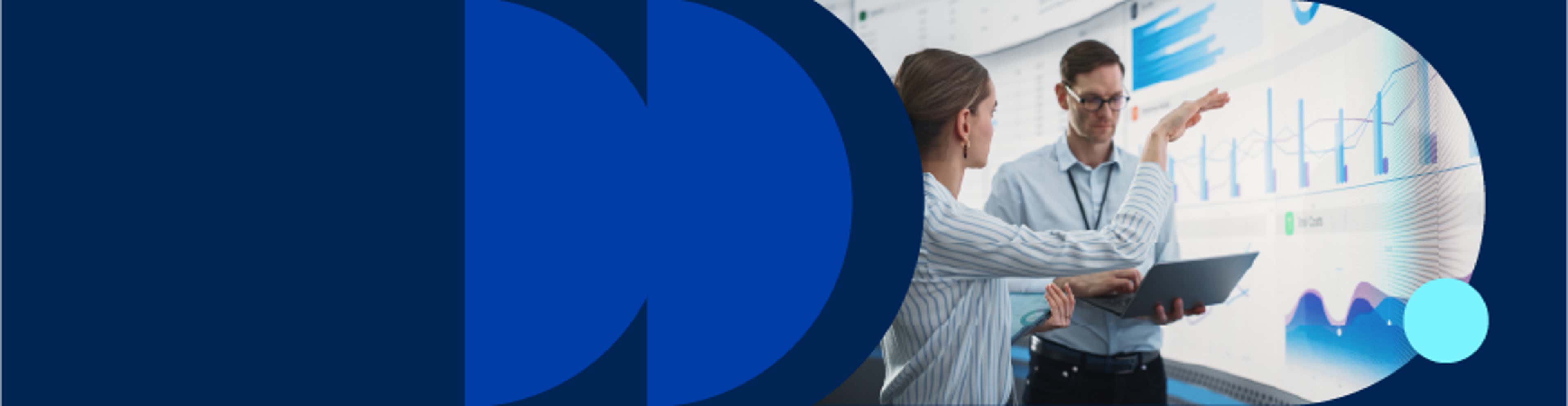 A man and woman analyze graphs displayed on a screen, discussing data insights together