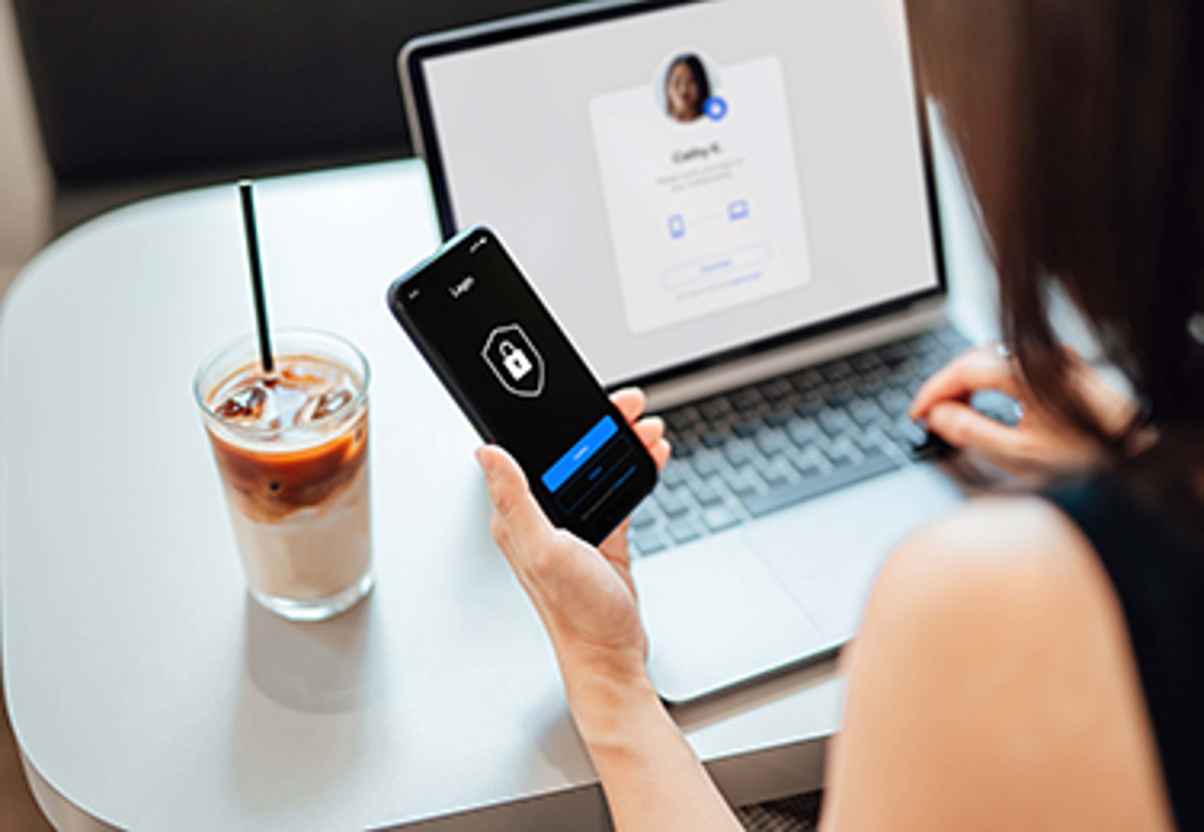 Person with laptop and coffee and phone in hand