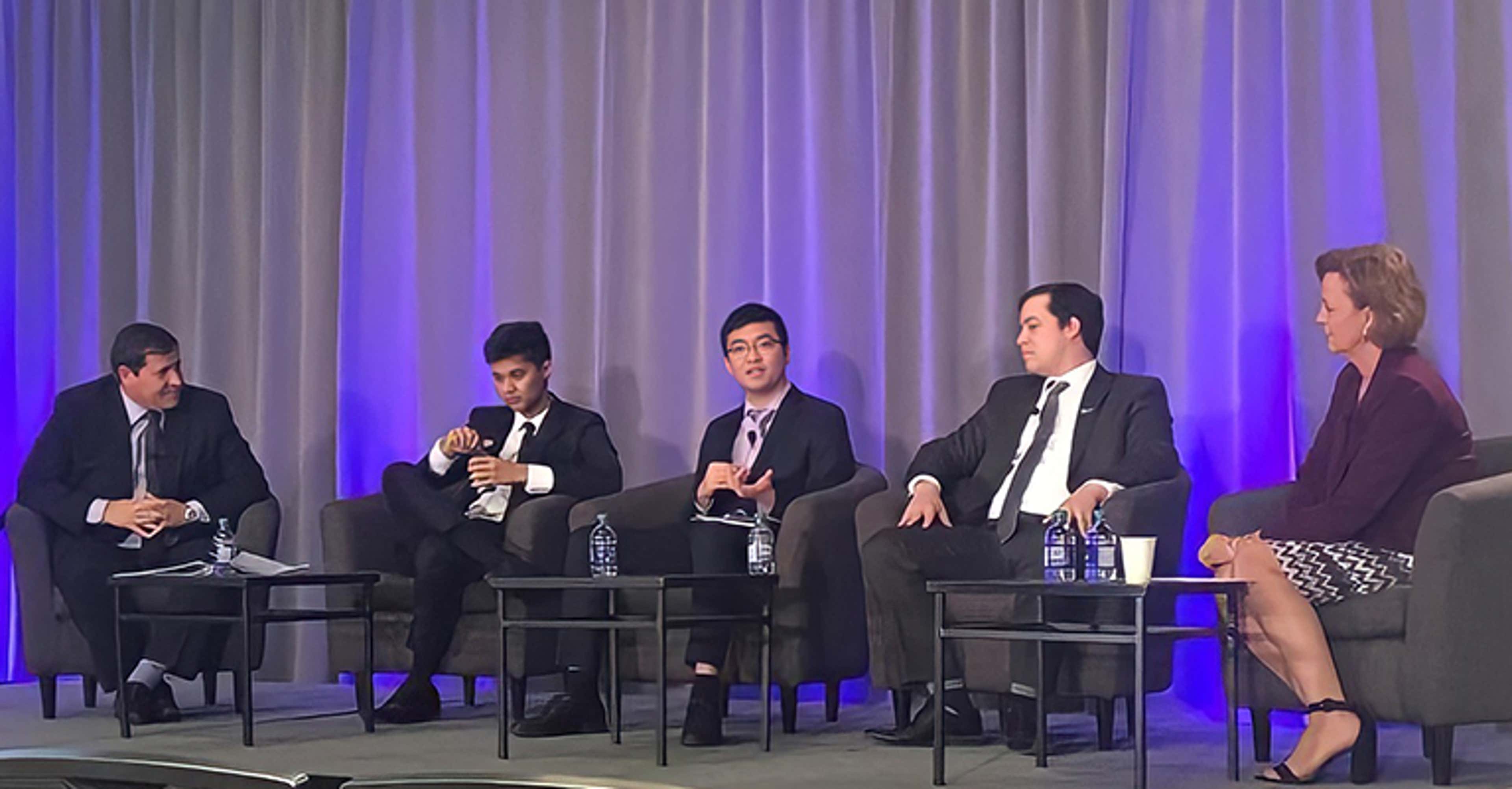 David Lao speaking in a panel on a stage