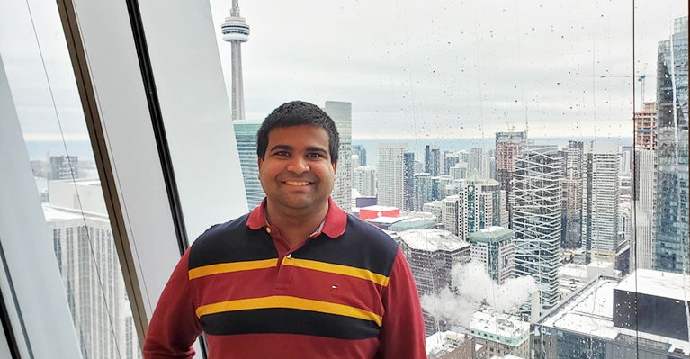 Photo of Dilshan Jayasinghe in office tower standing in front of window