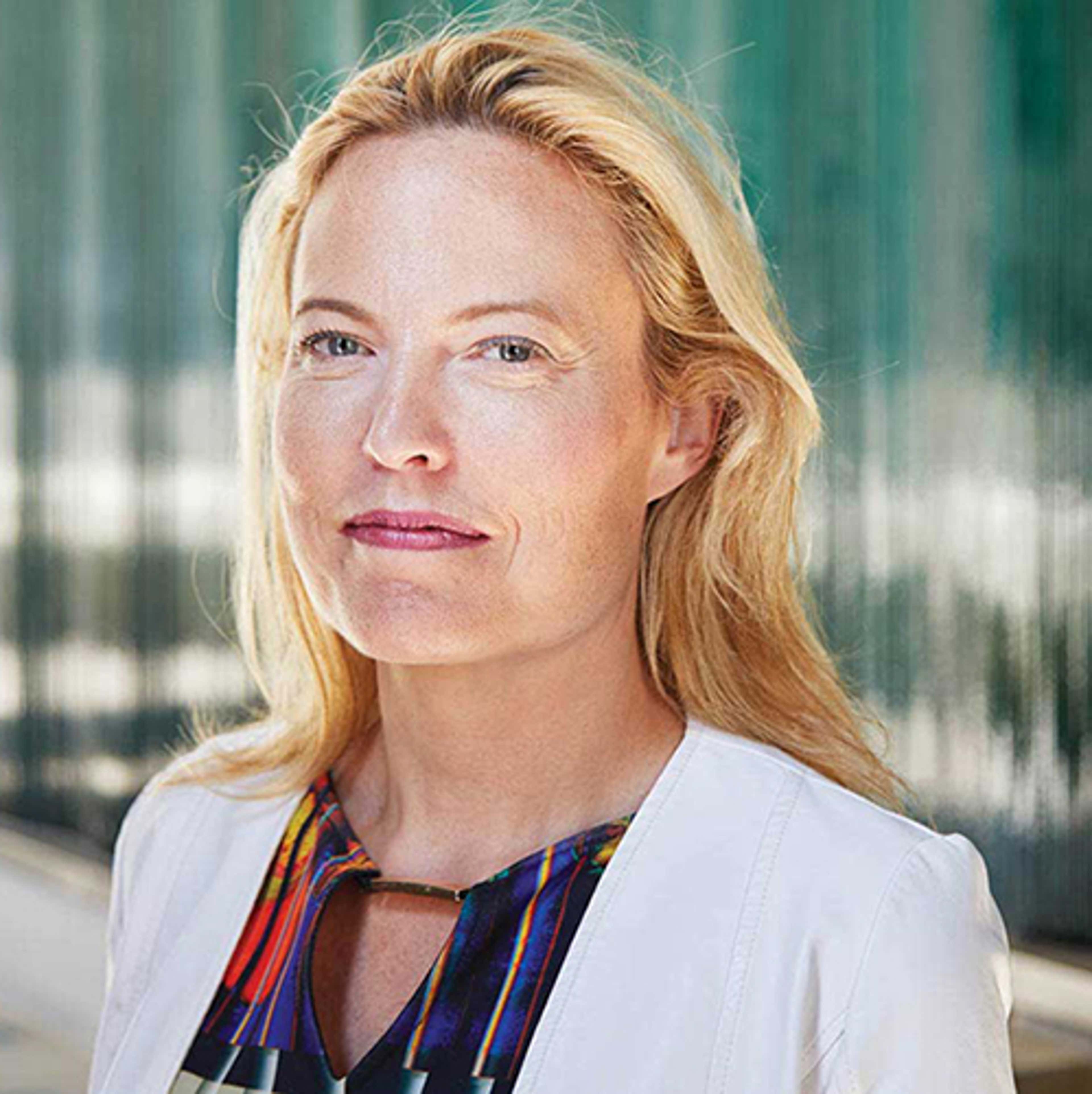 Headshot of Erin Kelly in white jacket and colourful shirt