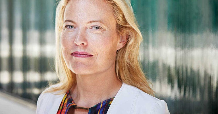 Headshot of Erin Kelly in white jacket and colourful shirt