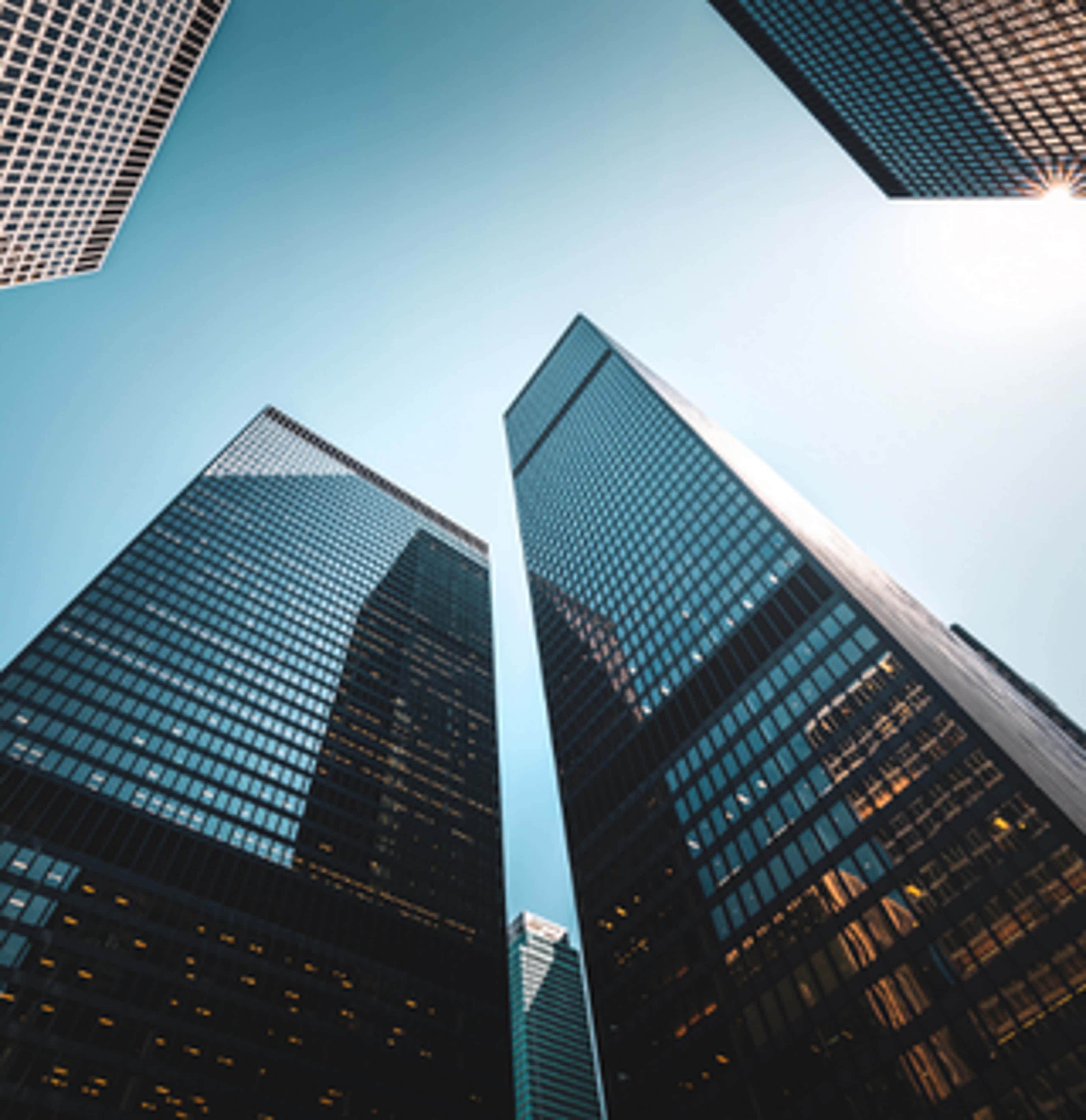 Tall city buildings with sunlight streaming through, creating a bright and vibrant urban atmosphere.