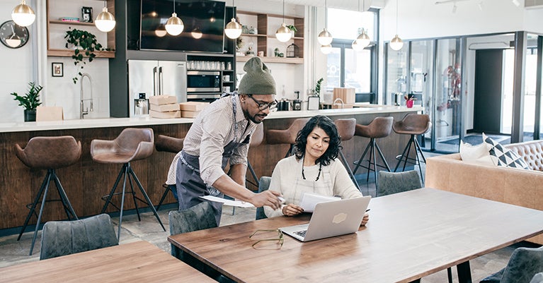 Two people sitting in cafe looking at laptop