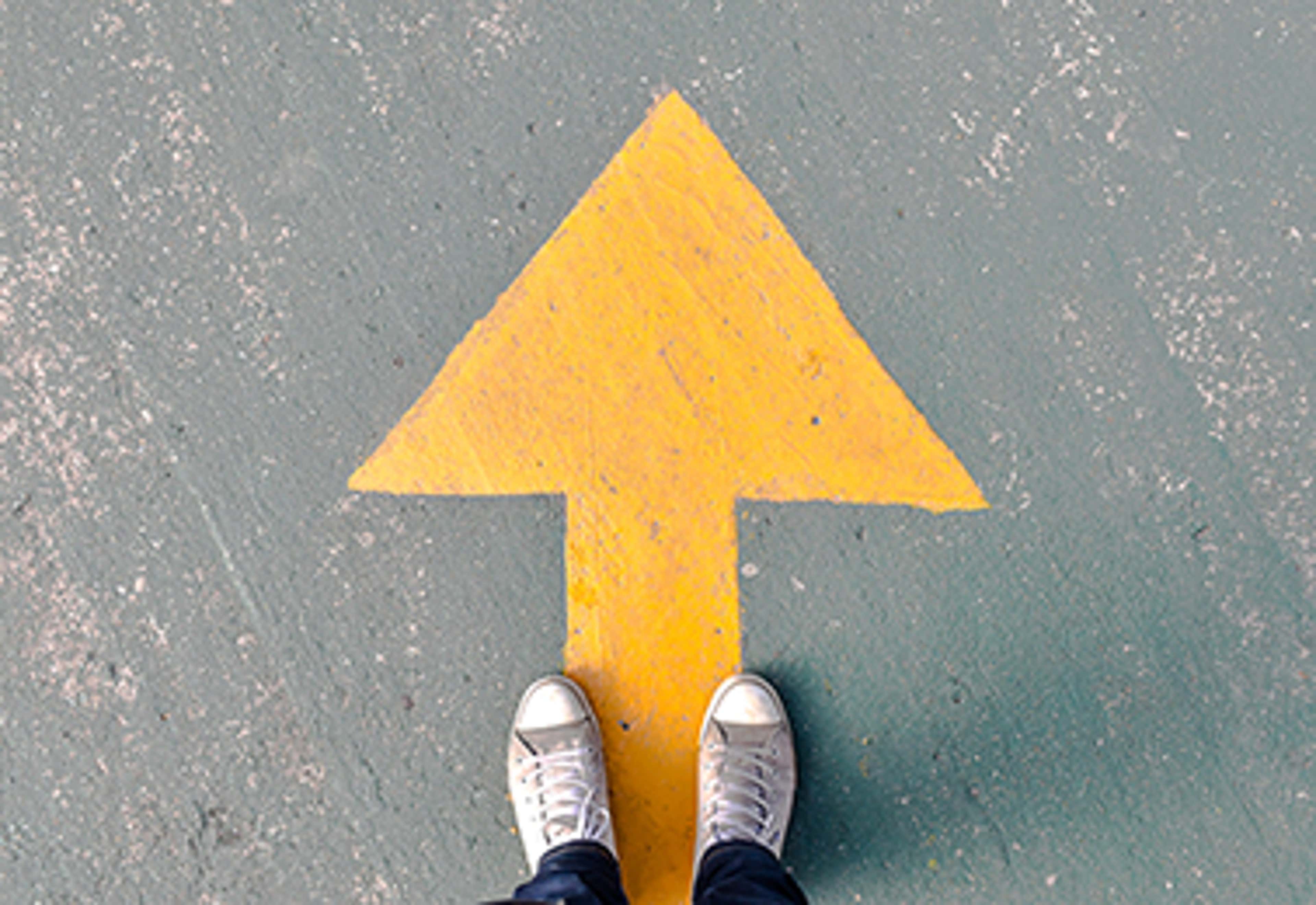 Yellow arrow on ground with feet at standing on it