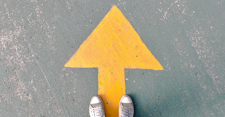 Yellow arrow on ground with feet at standing on it