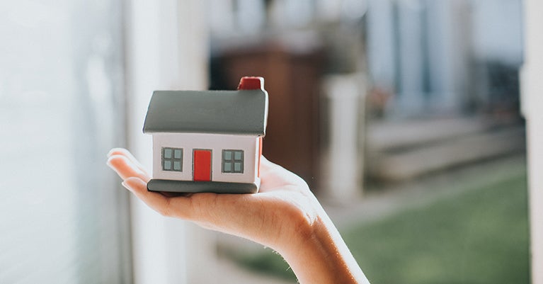 Hand holding a small model home decoration