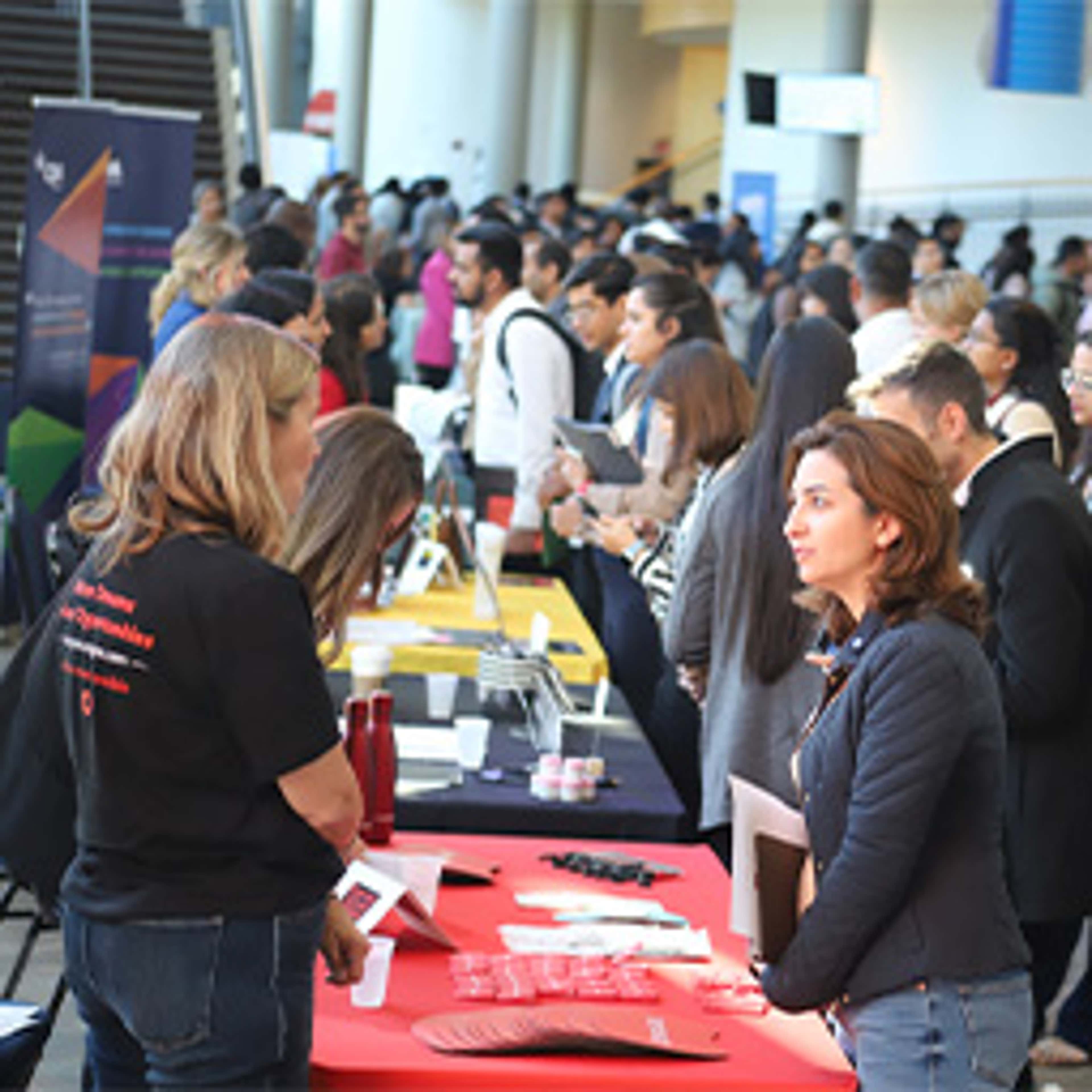Woman standing in front of booth speaking with another woman