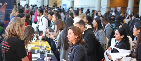 A career fair with people lining up in front of the booths.
