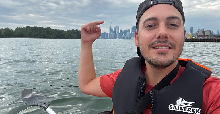 Picture of Jake out in Lake Toronto pointing to the CN Tower