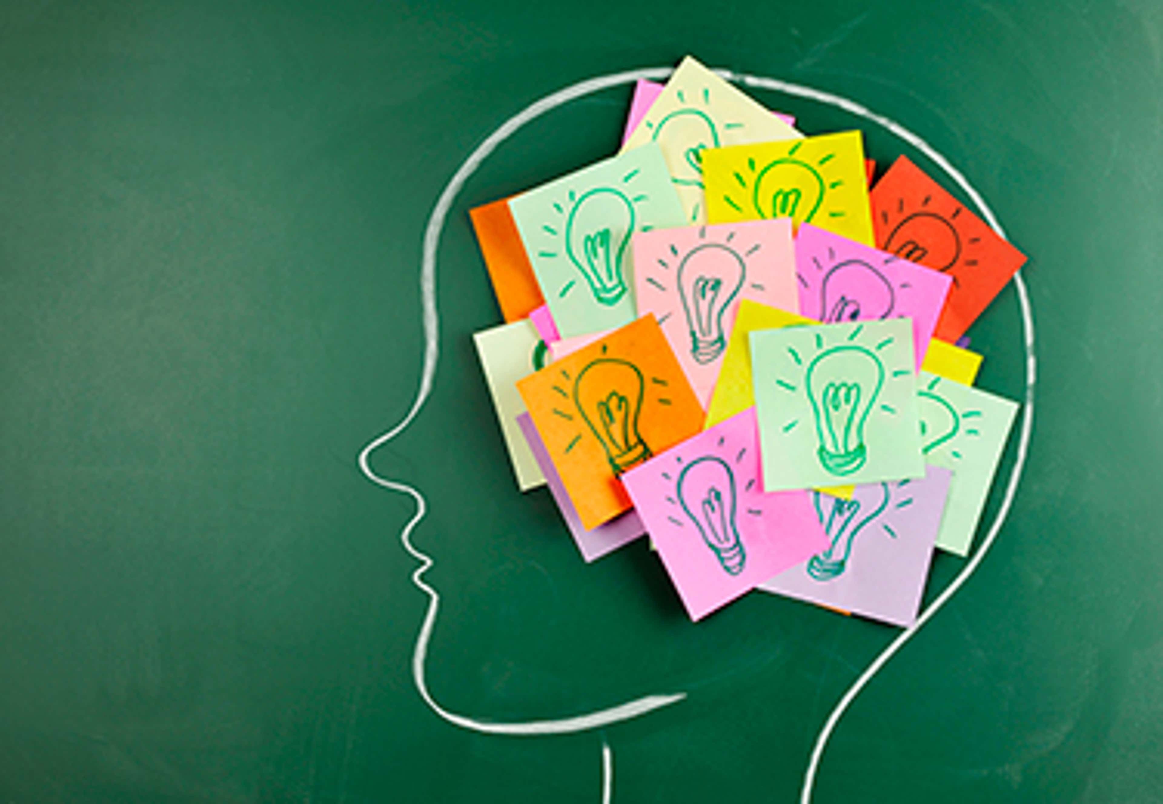 Chalkboard with head drawn on it with post-it notes with lightbulbs in it