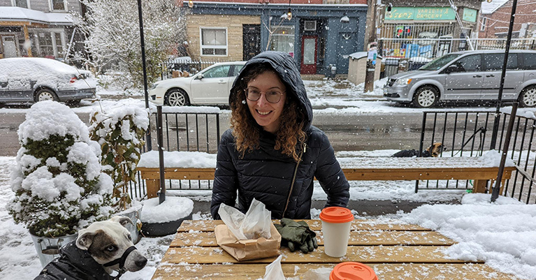 Madison sitting at a table outdoors while it's snowing
