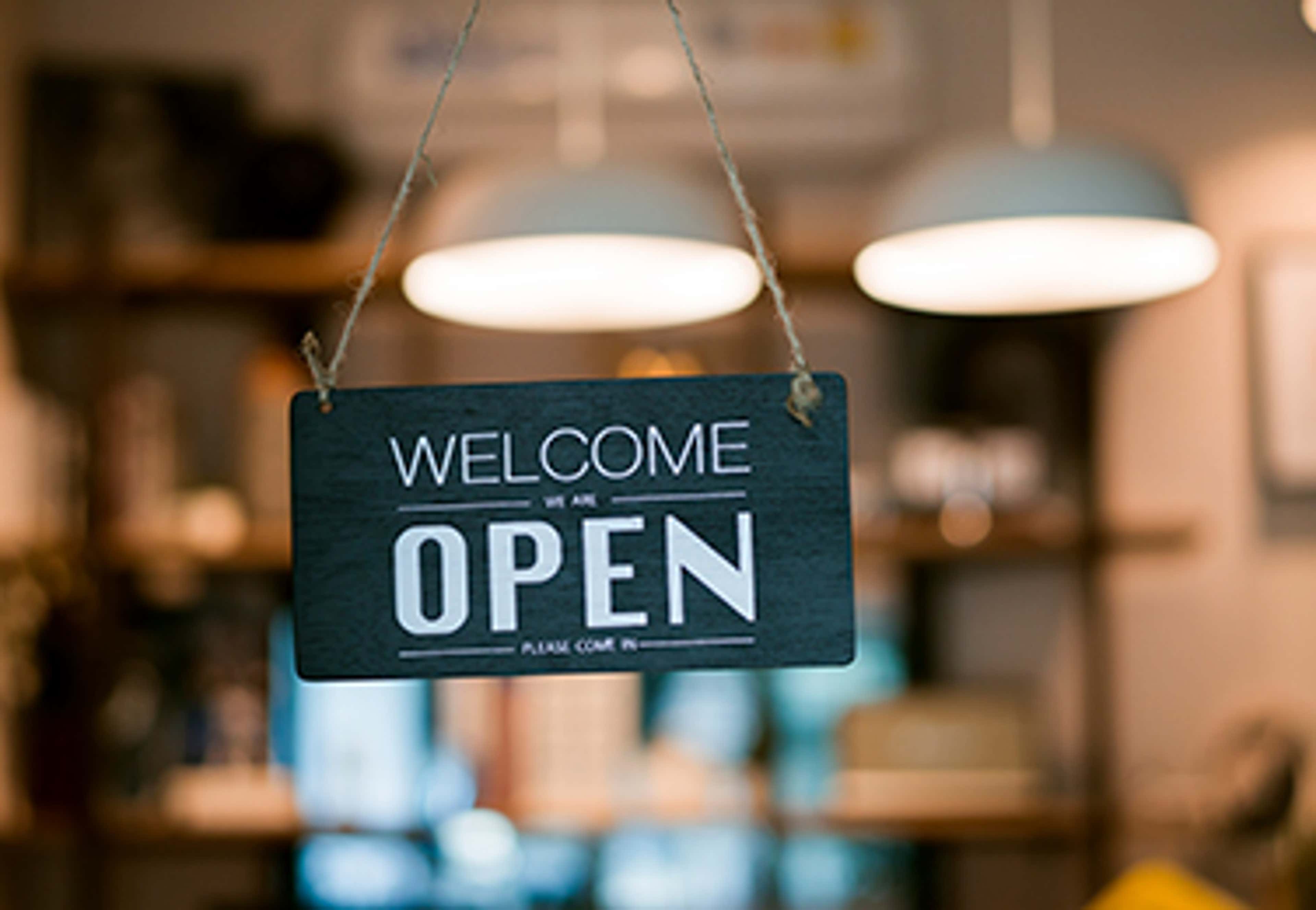 Welcome Open sign hanging on glass door
