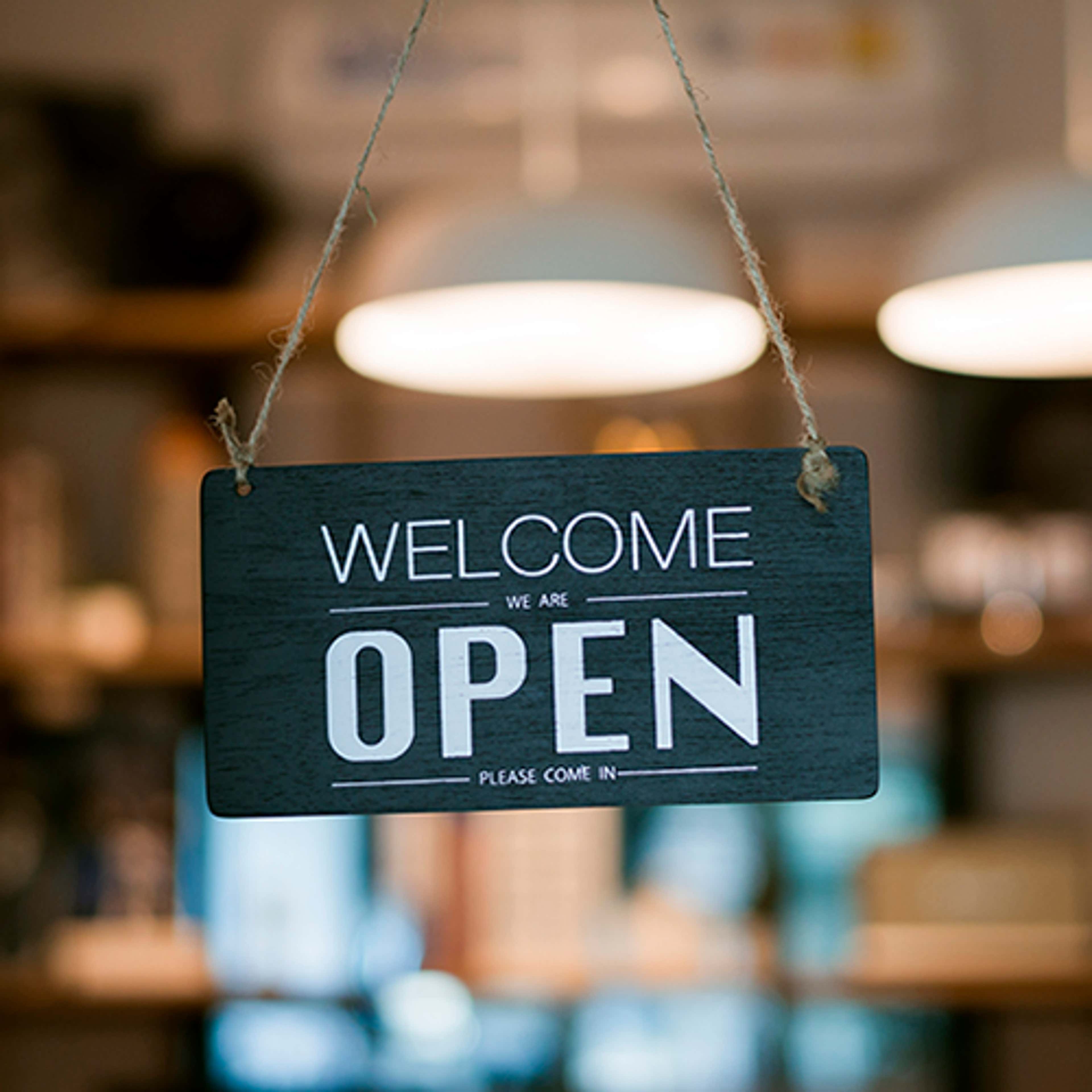 Sign on door with words welcome we are open