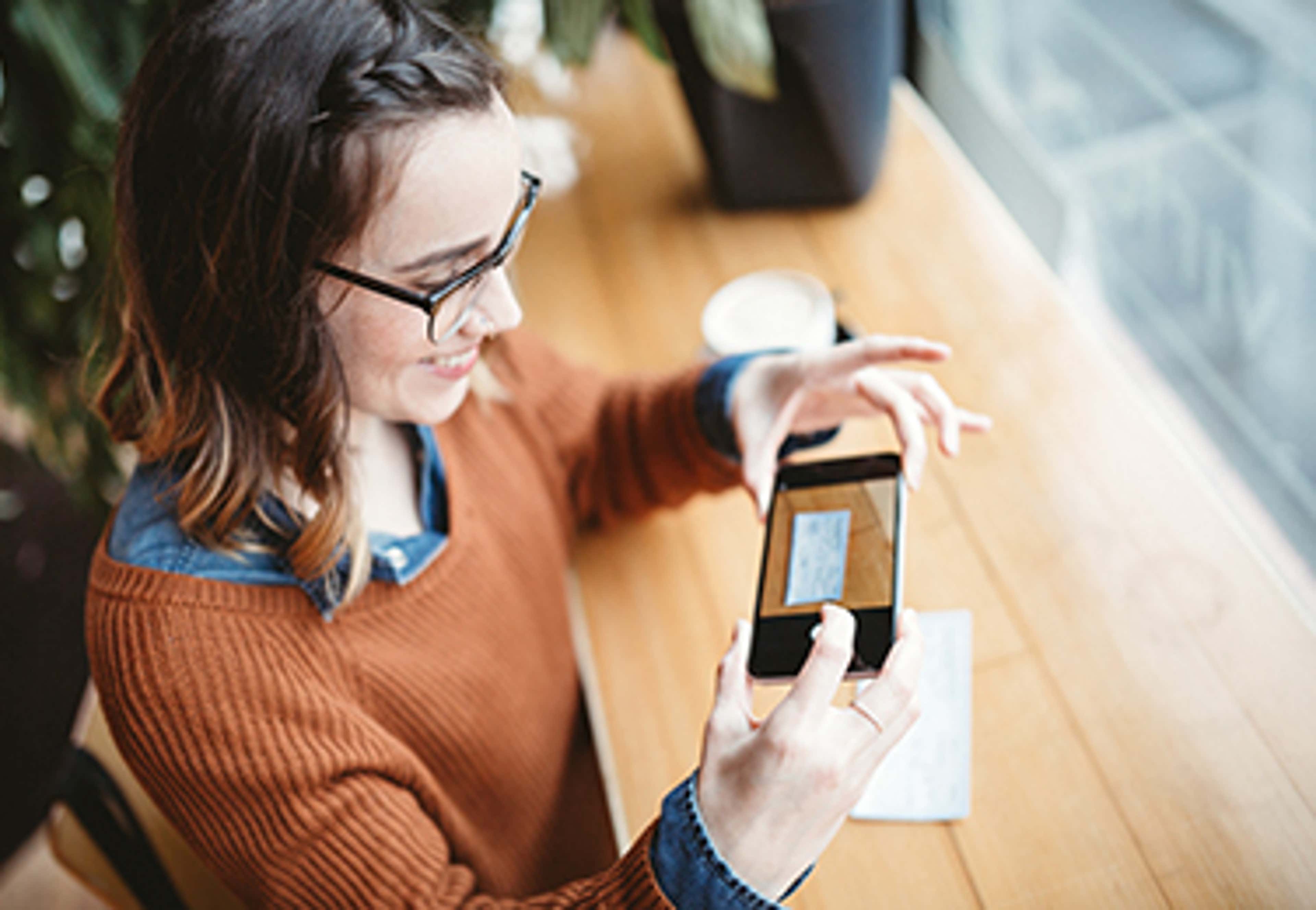 Person holding cell phone taking photo of cheque
