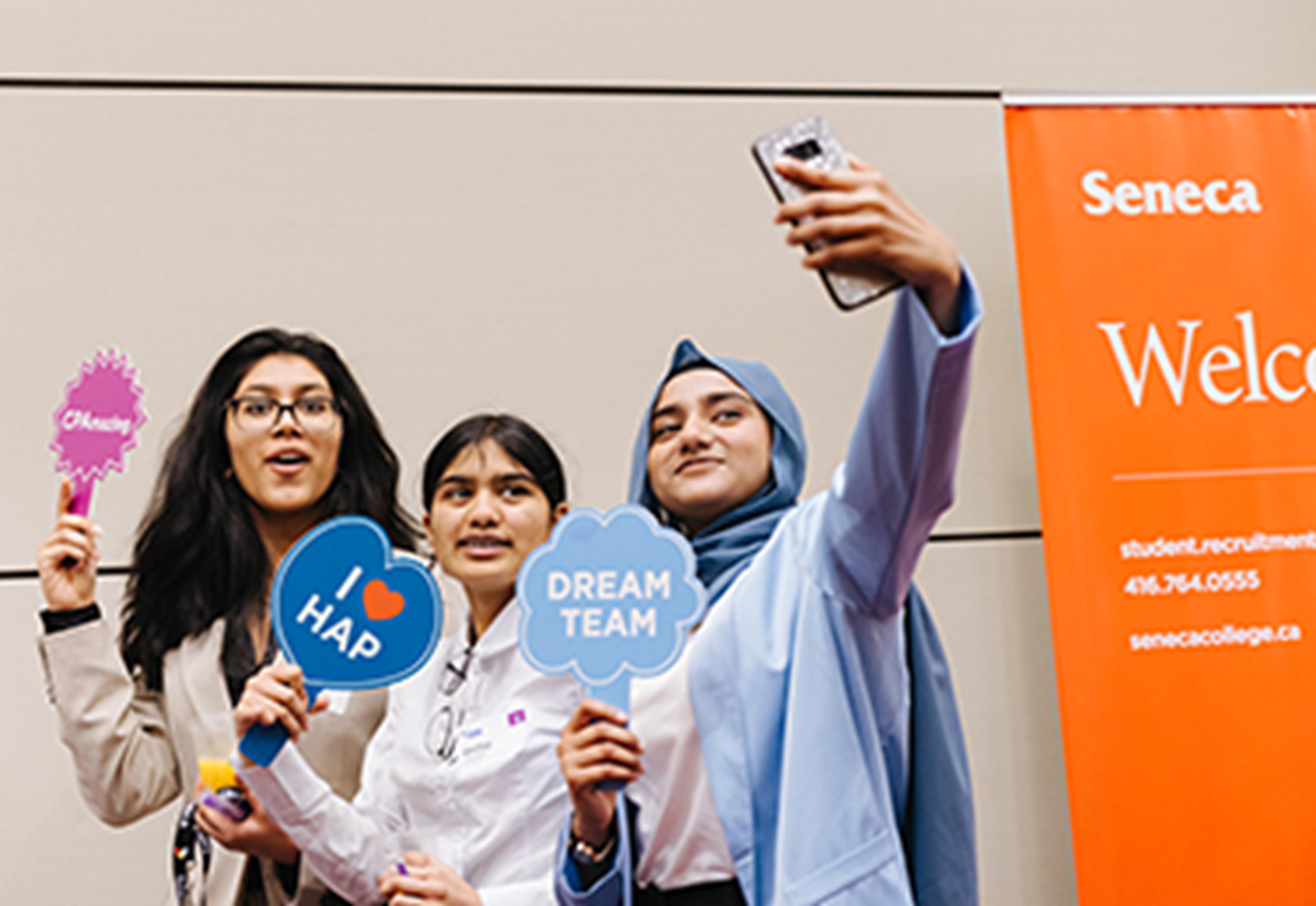 Three students taking selfies and holding CPA signs