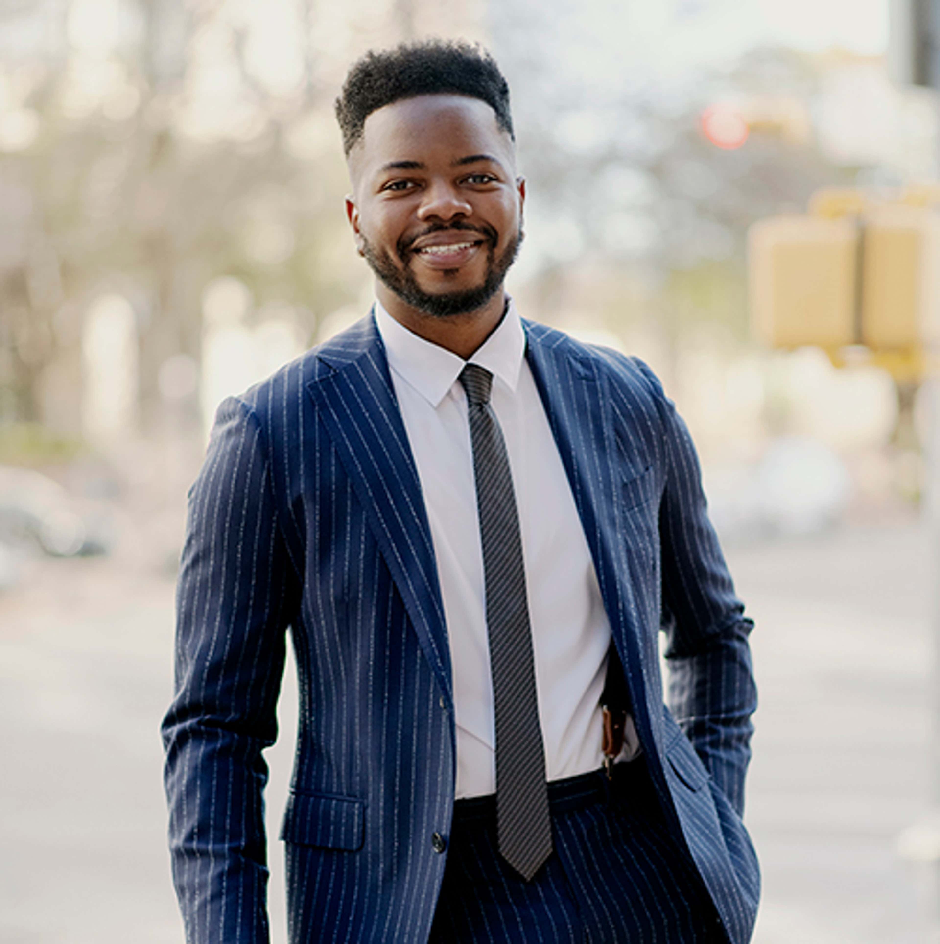 Rony Fogain standing in a blue suit smiling at camera