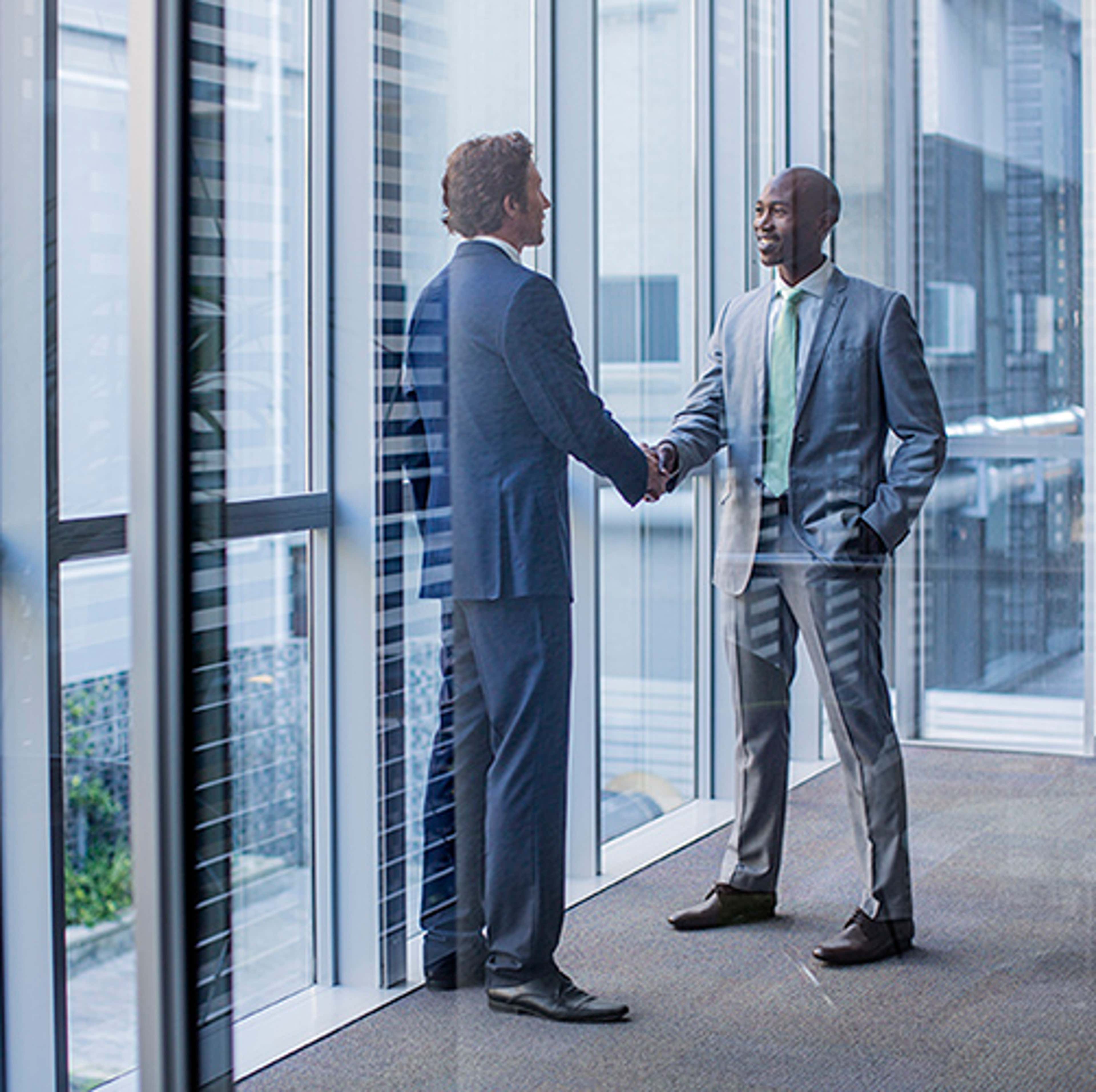 Two men in suits shaking hands in office