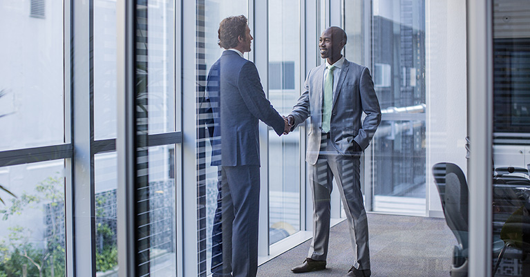 Two men in suits shaking hands in office