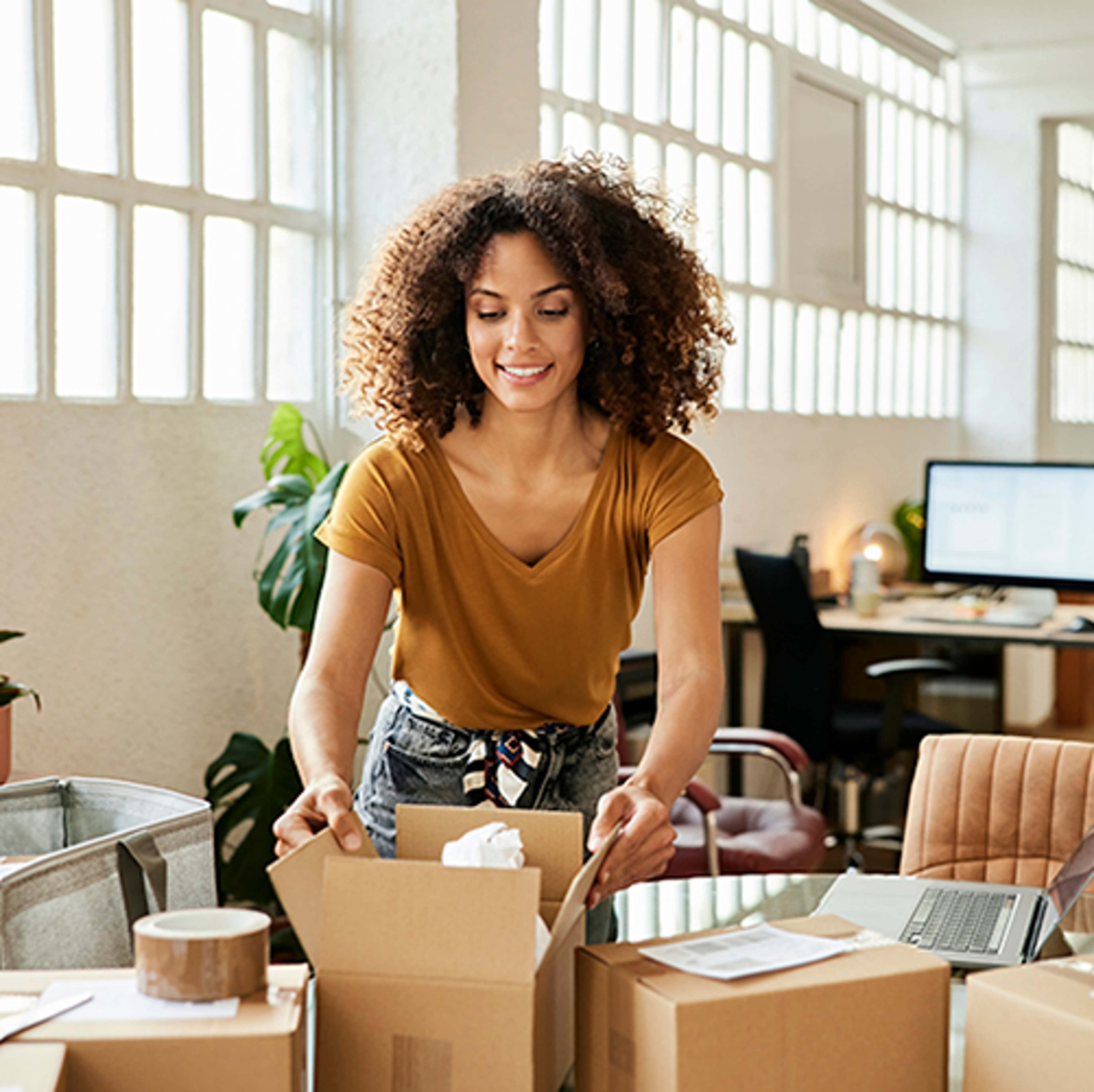 Woman leaning over table closing boxes for an order