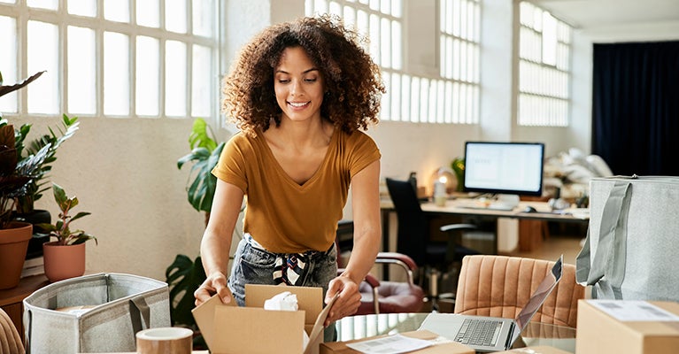 Woman leaning over table closing boxes for an order