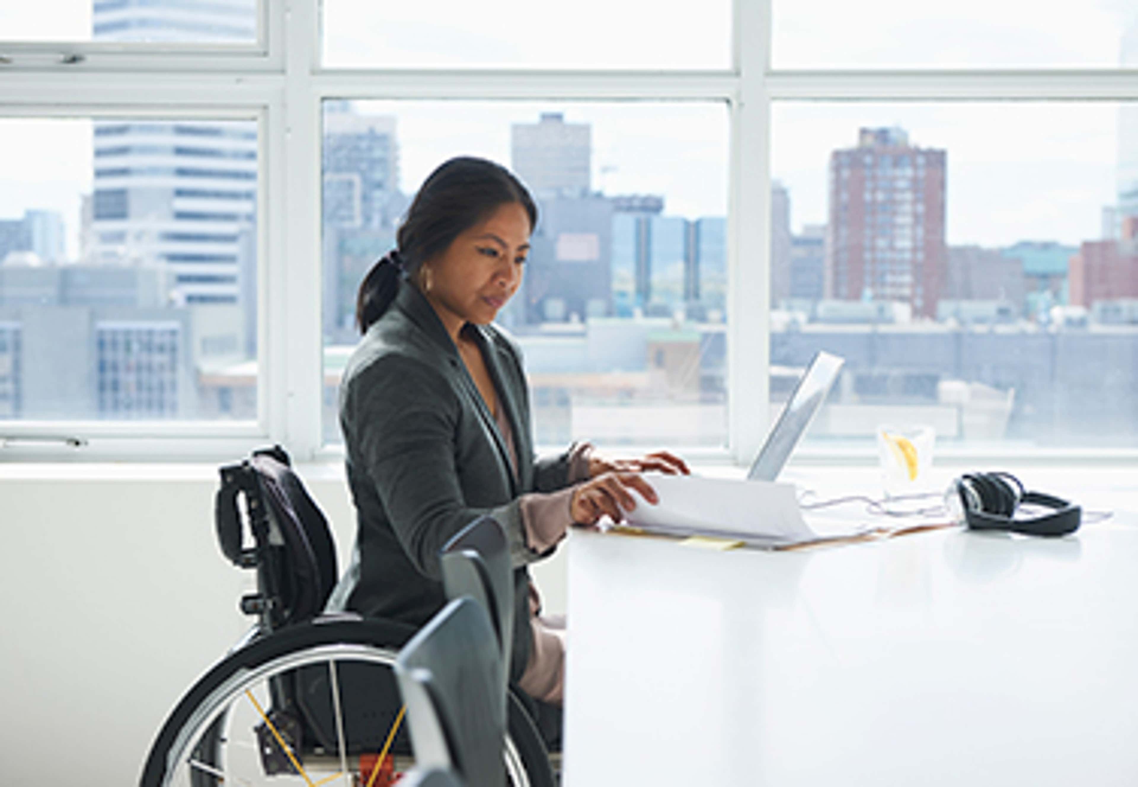Woman in wheelchair at a desk with a laptop