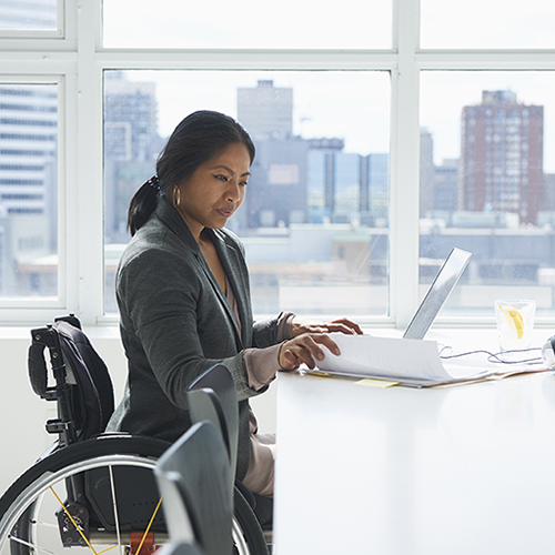 Woman in wheelchair at a desk with a laptop