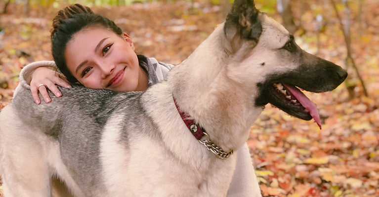 Della Wang in a forest with a German shepherd dog