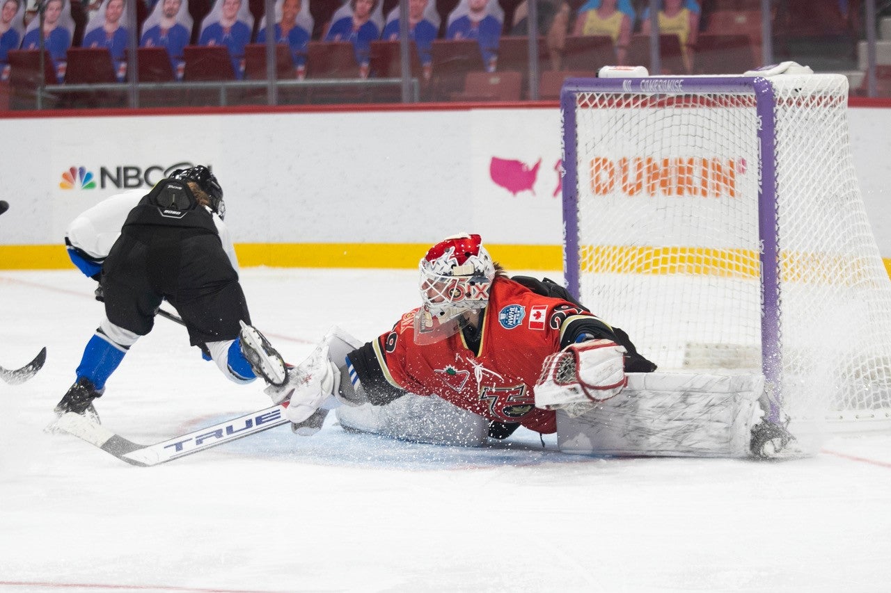 Elaine stopping a shot in the net as a hockey goalie