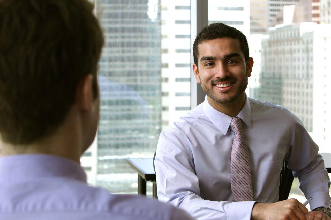 Fahad Meer sitting at table looking at camera and smiling