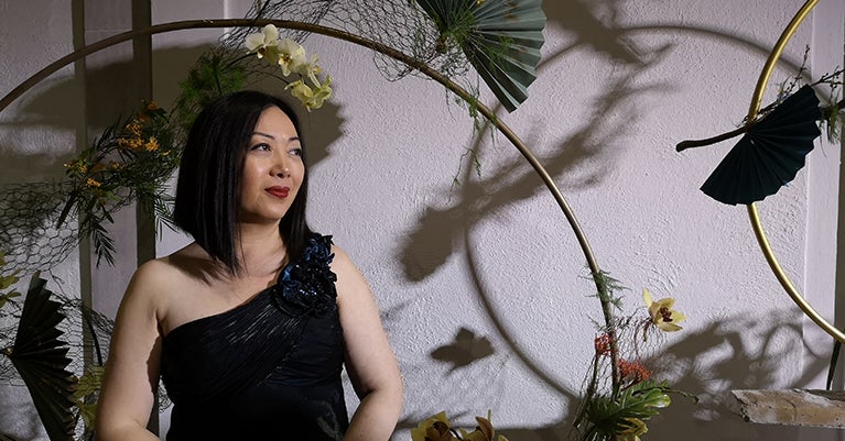 Janet in a darkened room surrounded by plants and decorations.