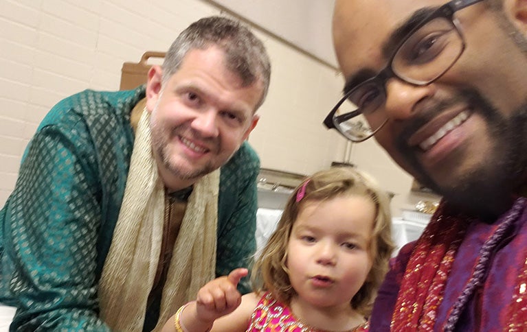 Rishi with a man and a young girl, all looking at camera and smiling