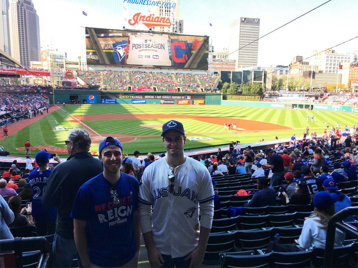 Josh Hoffman with a former Blue Jays colleague smiling at camera overlooking the baseball diamond at Game 2 of the 2016 ALCS in Cleveland