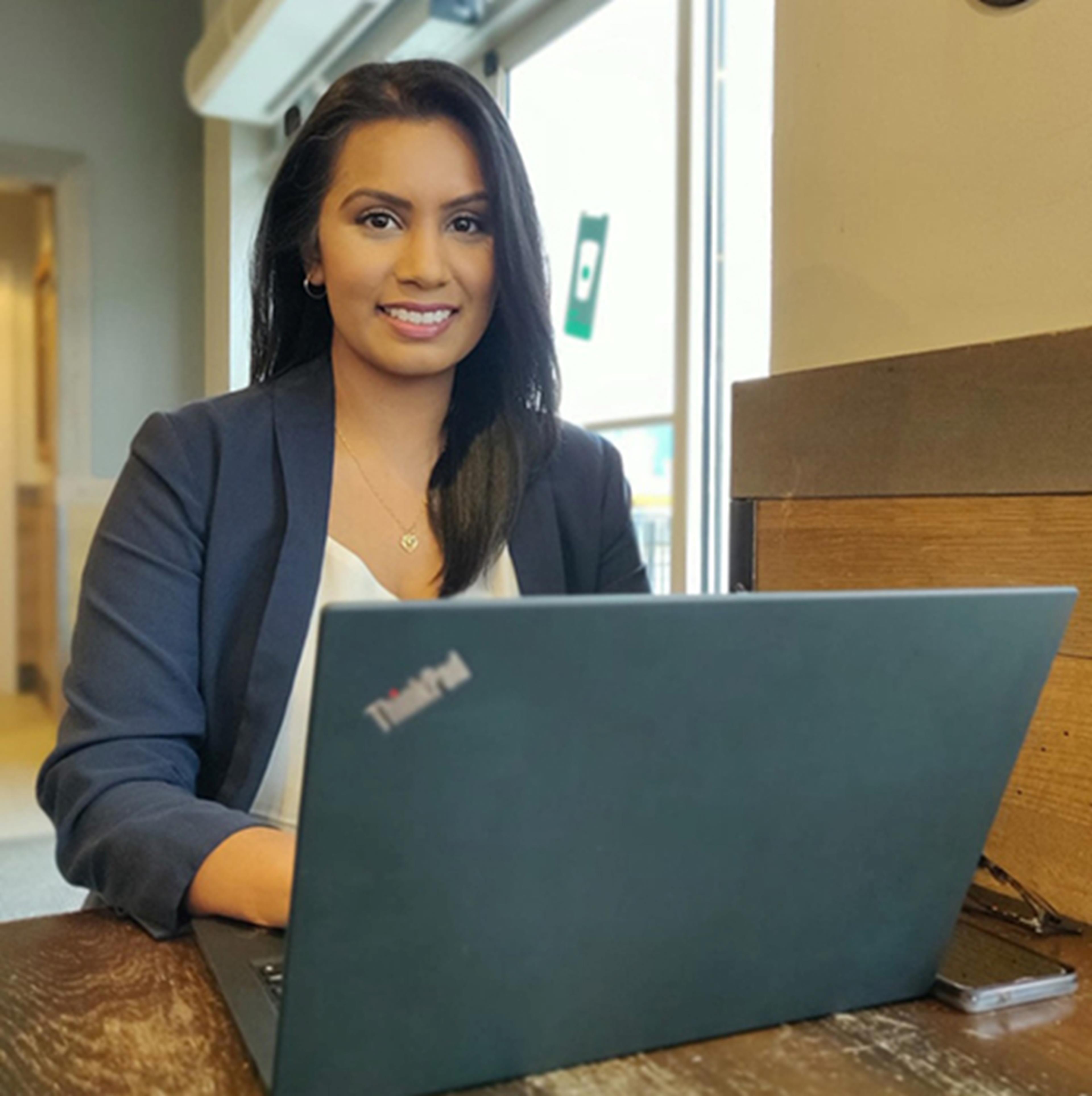 Tracy Singh sitting at desk with laptop in coffee shop