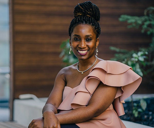 Vivienne Lutwama sitting in a salmon colored formal blouse, smiling at the camera