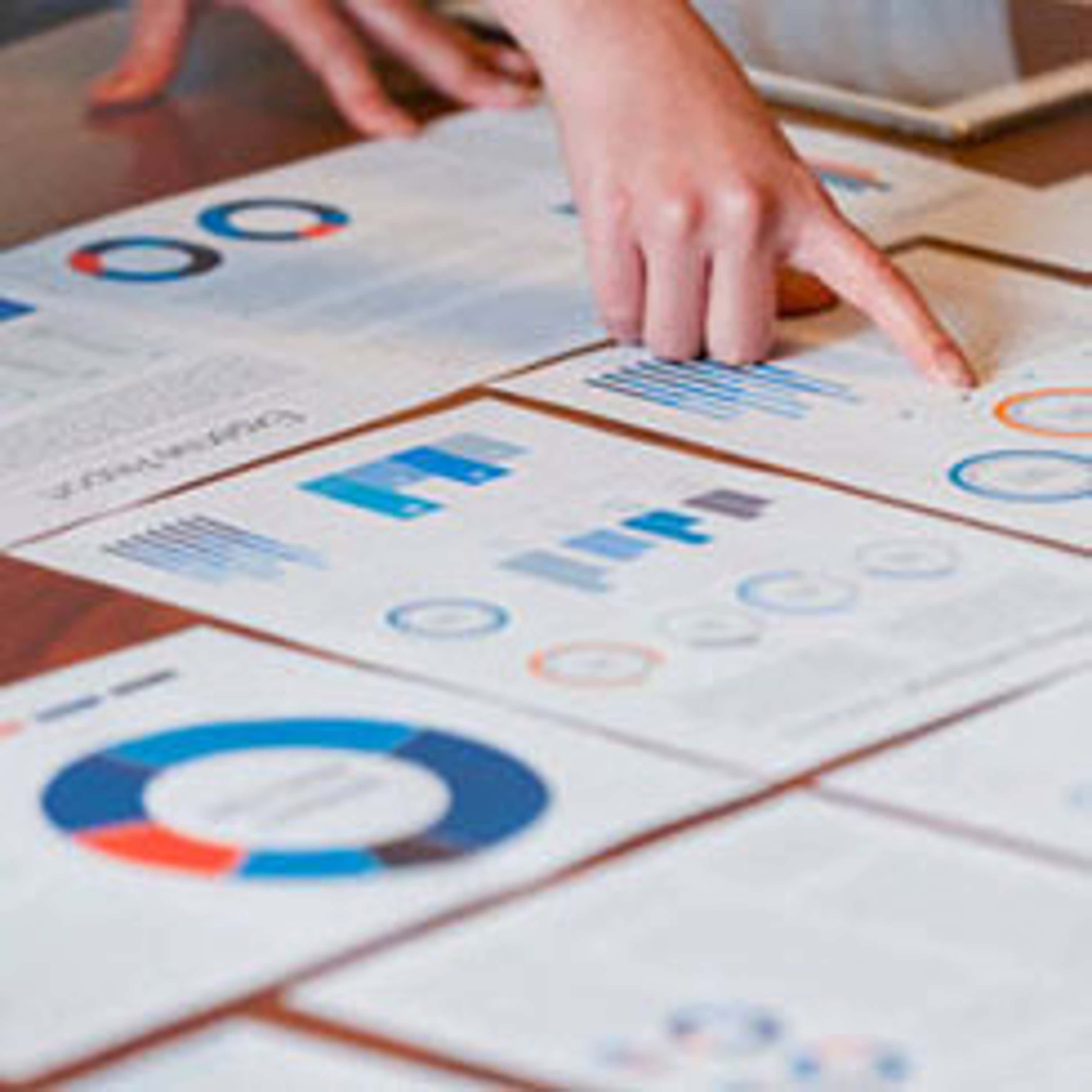 Hand pointing to papers with charts on a table