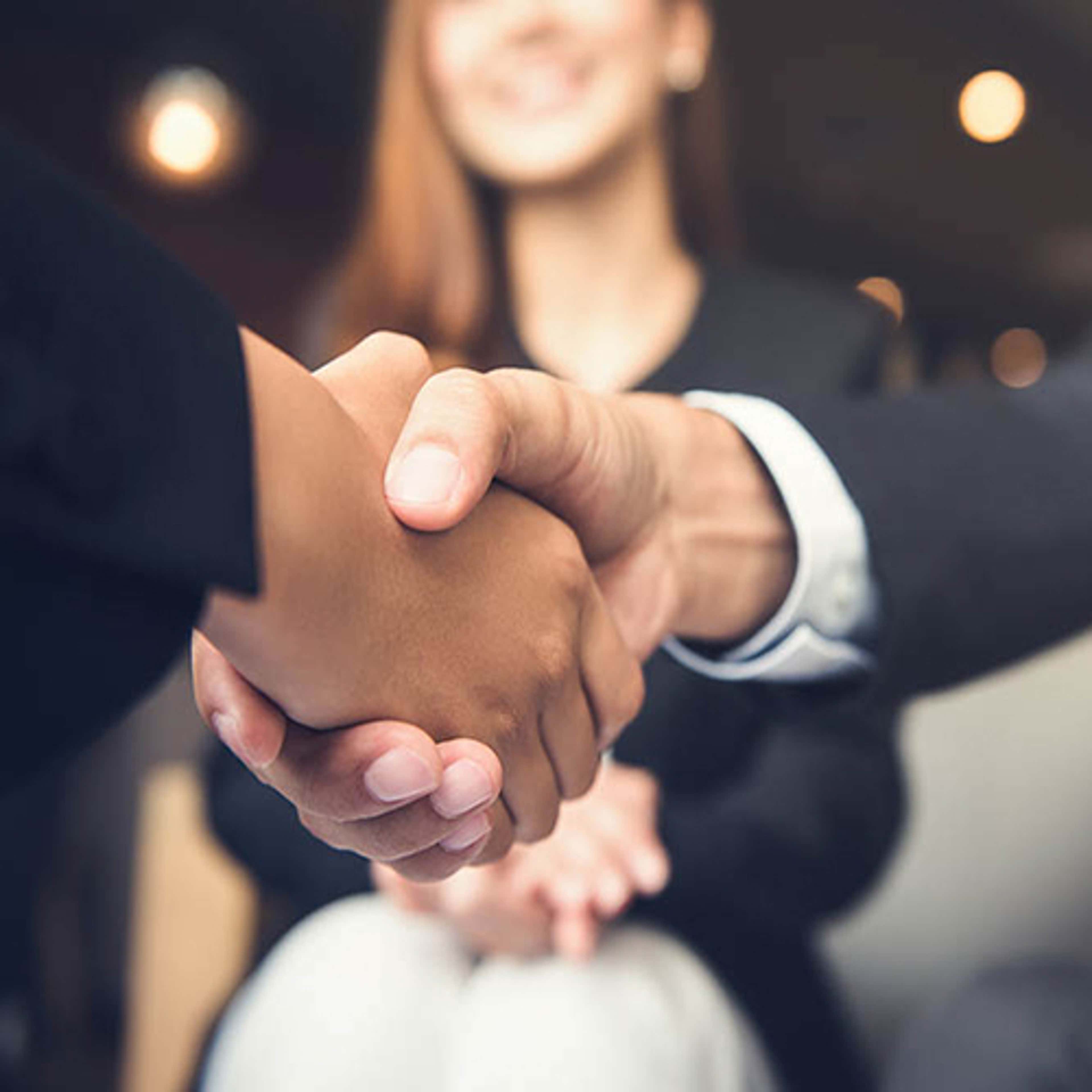 Hands shaking with person in background