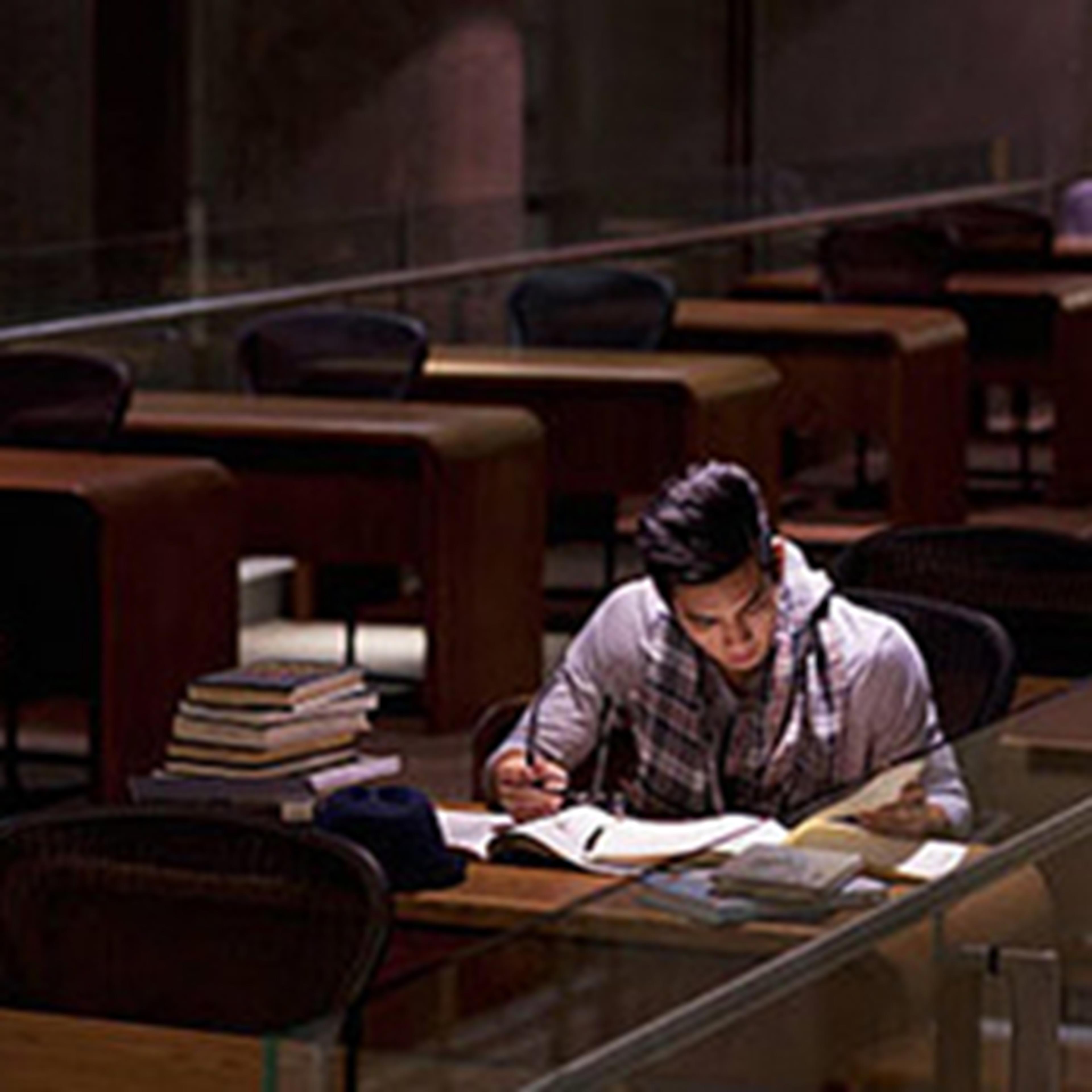 Lone person studying with books in large empty library