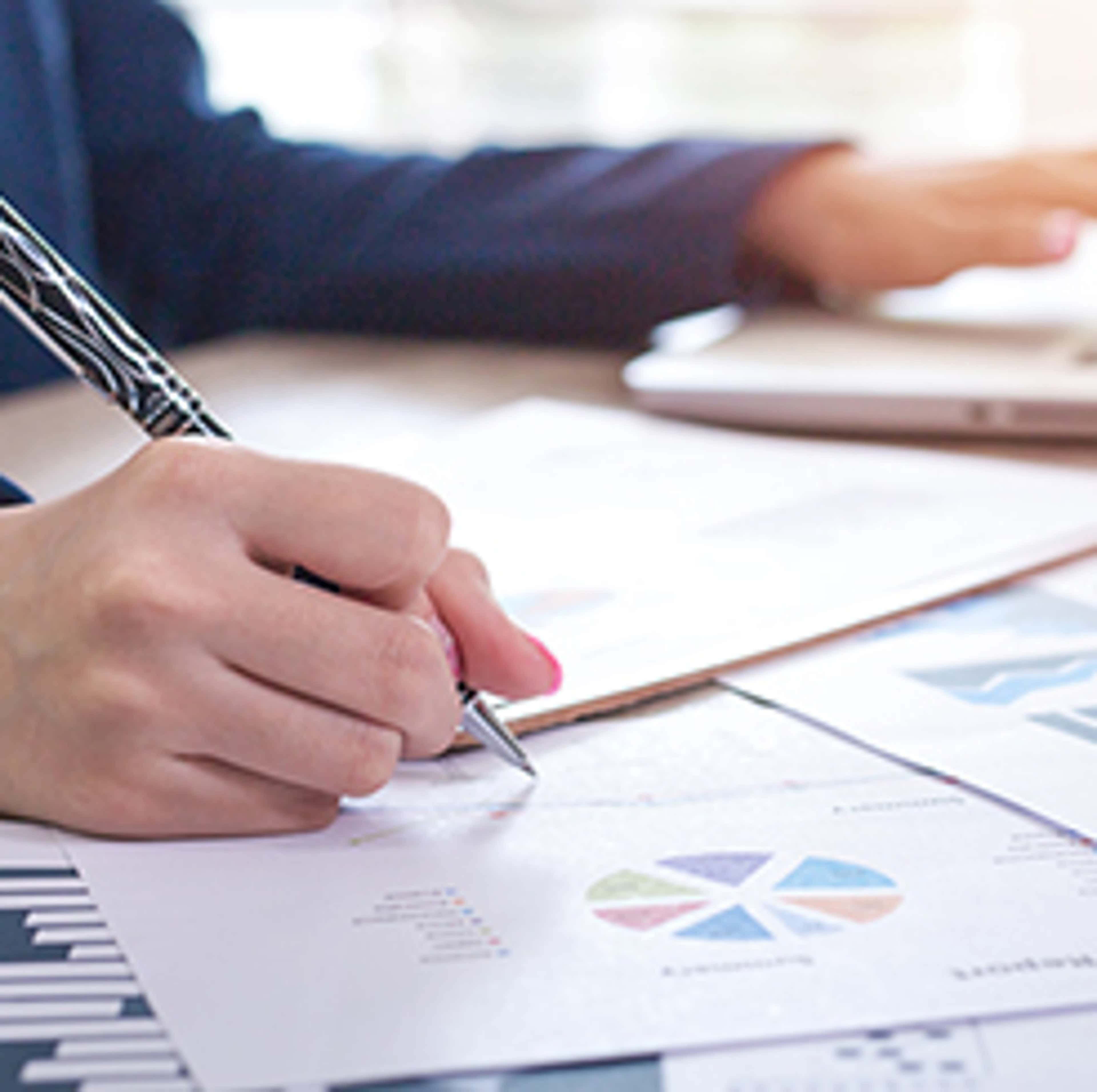 Person writing on paper with charts