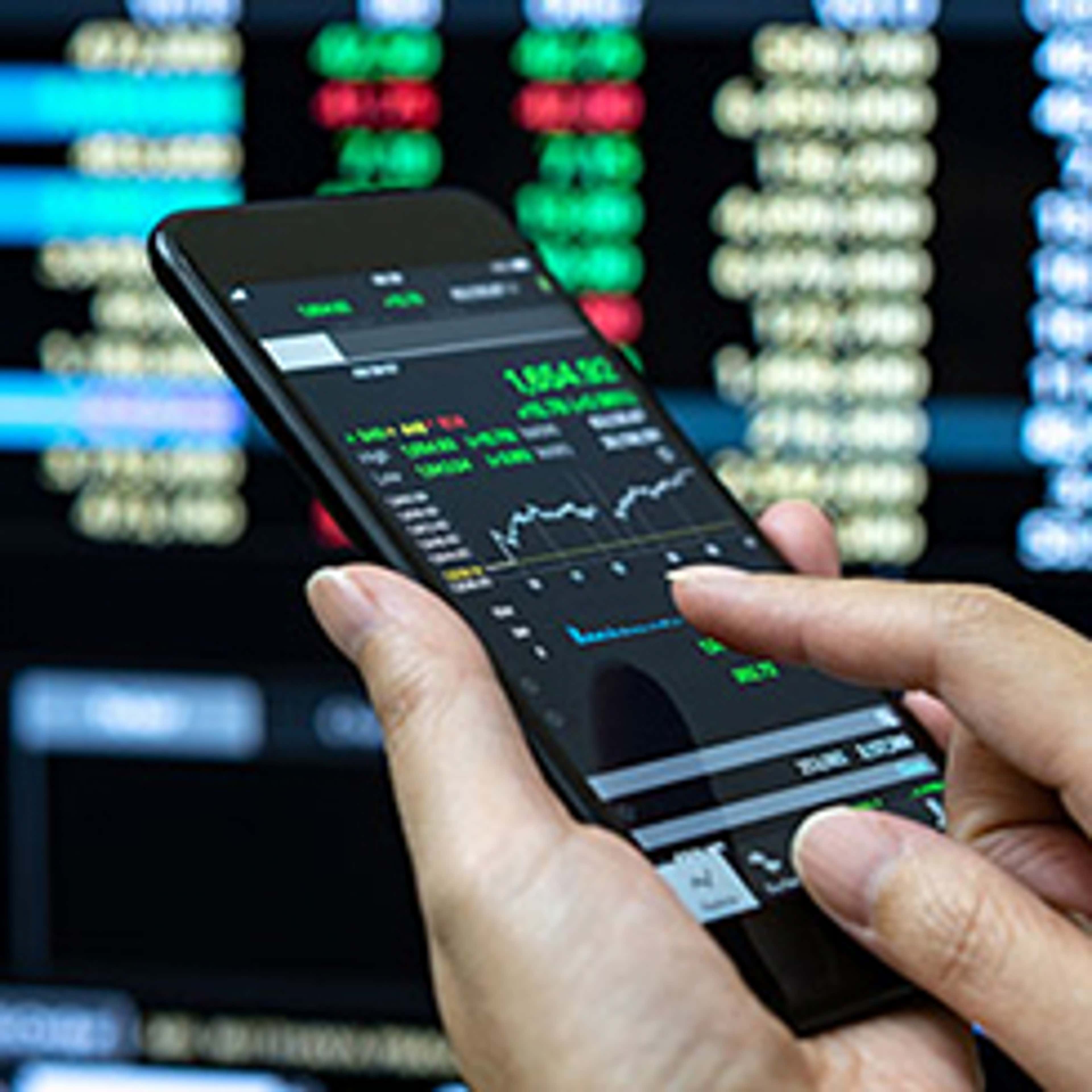 Hand holding phone showing stock market graph